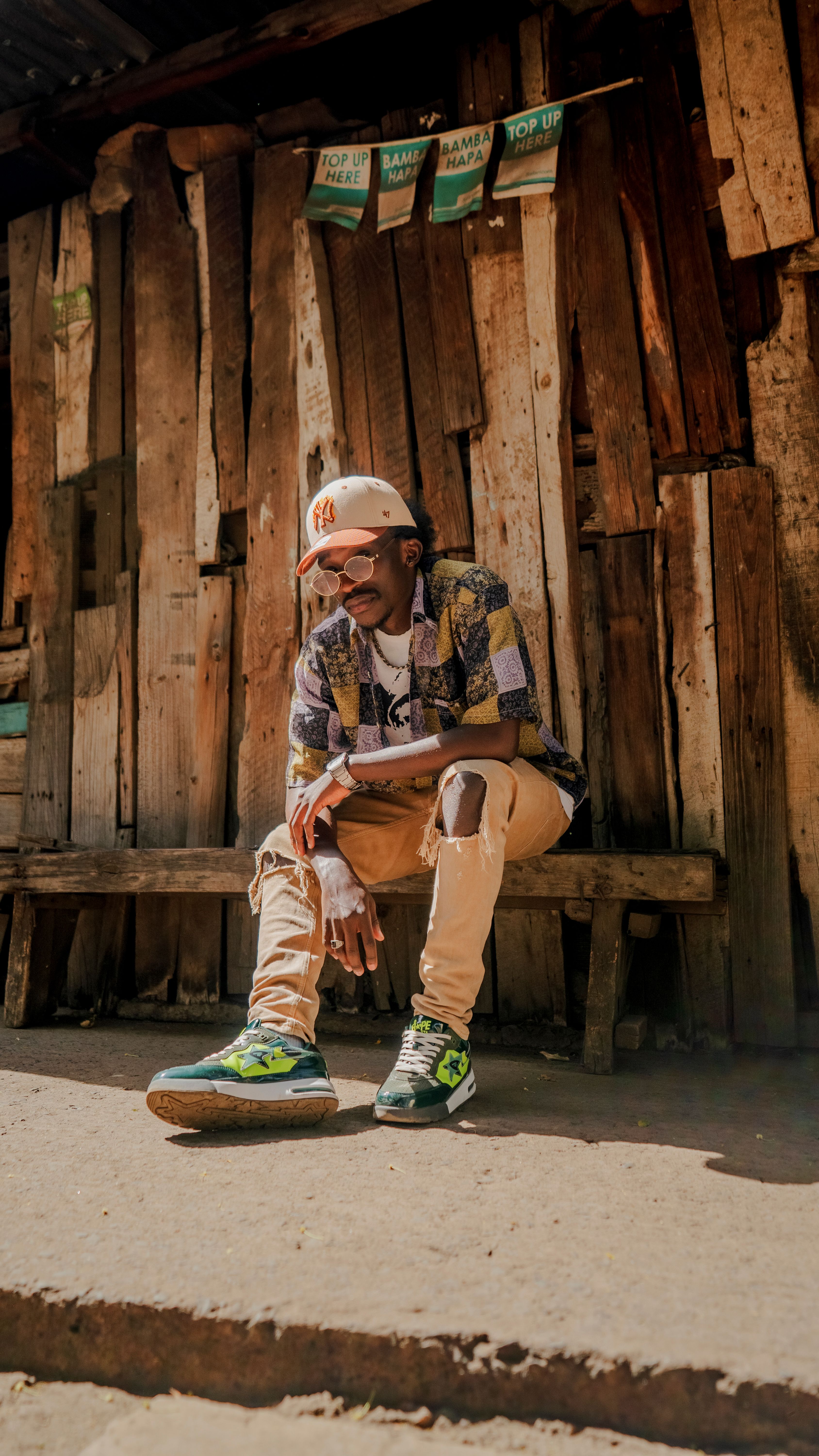 Young man in casual streetwear sitting on a bench in Nairobi, Kenya, showcasing urban African fashion.