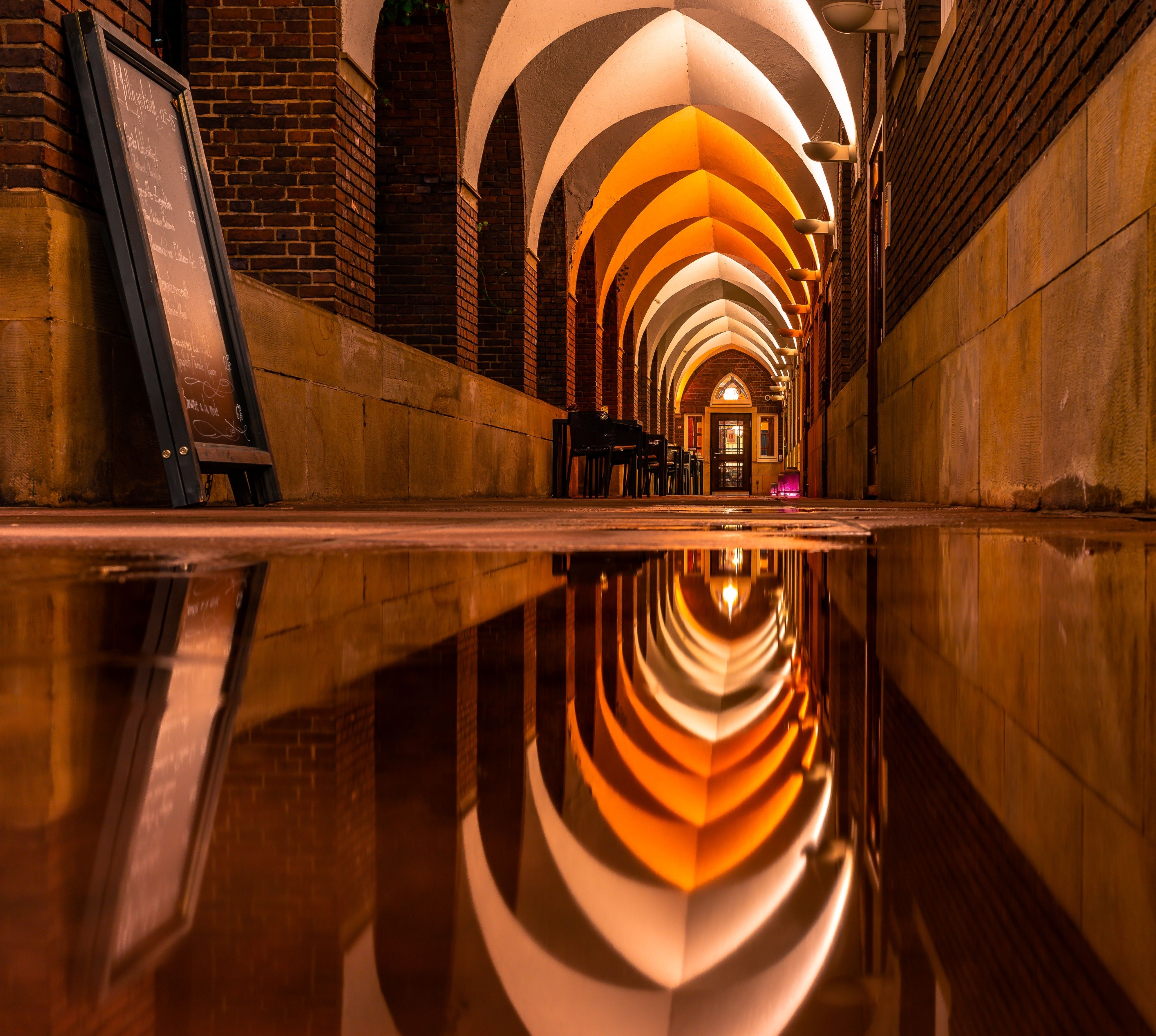 Stunning night view of an illuminated arched corridor with water reflection.