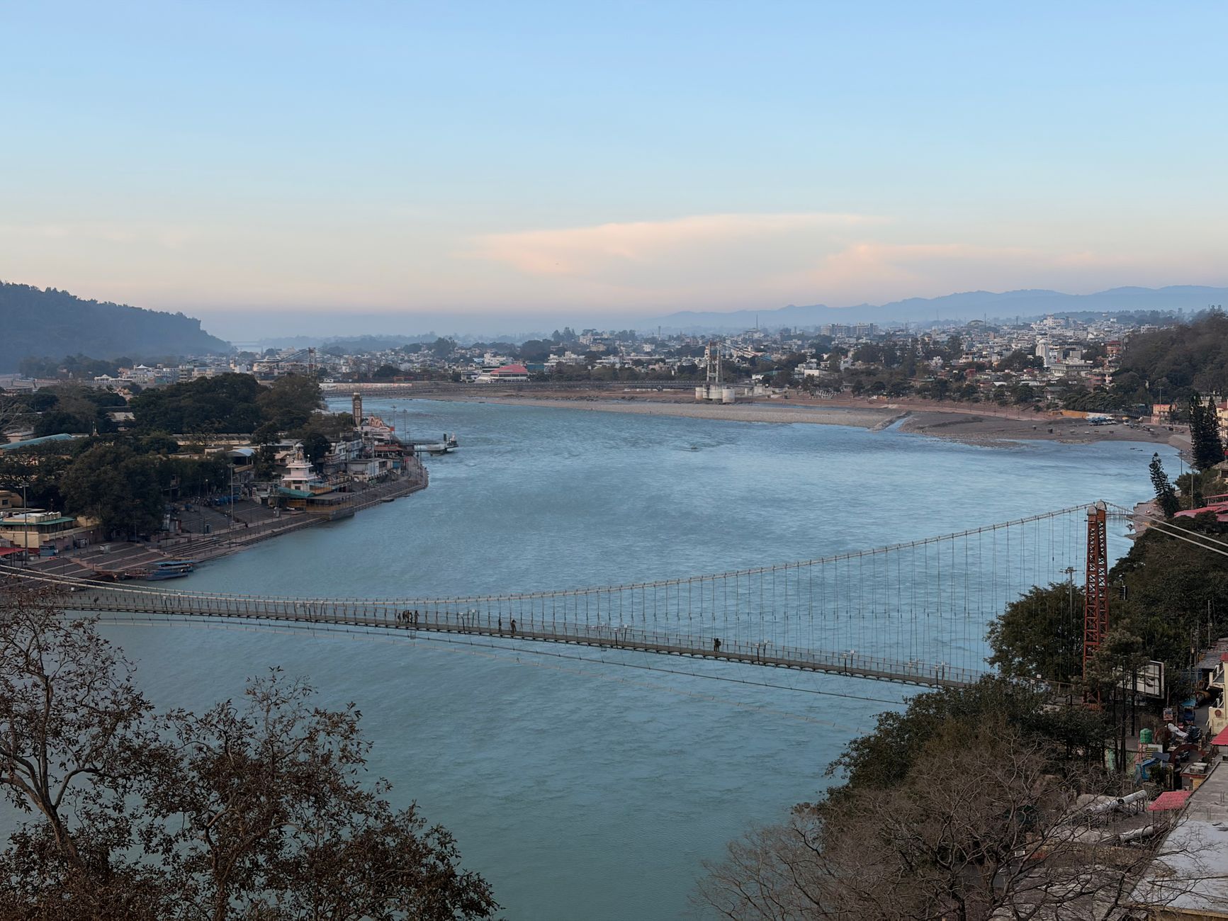 A breathtaking view of the iconic Laxman Jhula bridge in Rishikesh over the Ganges River during daytime.