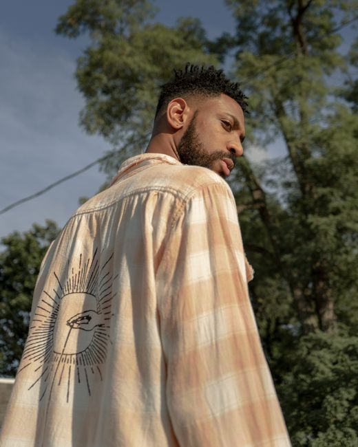 A fashionable man posing in a plaid shirt with a unique design, outdoors