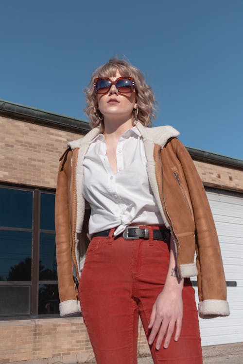 Woman Wearing White Top, Red Pants and Brown Jacket