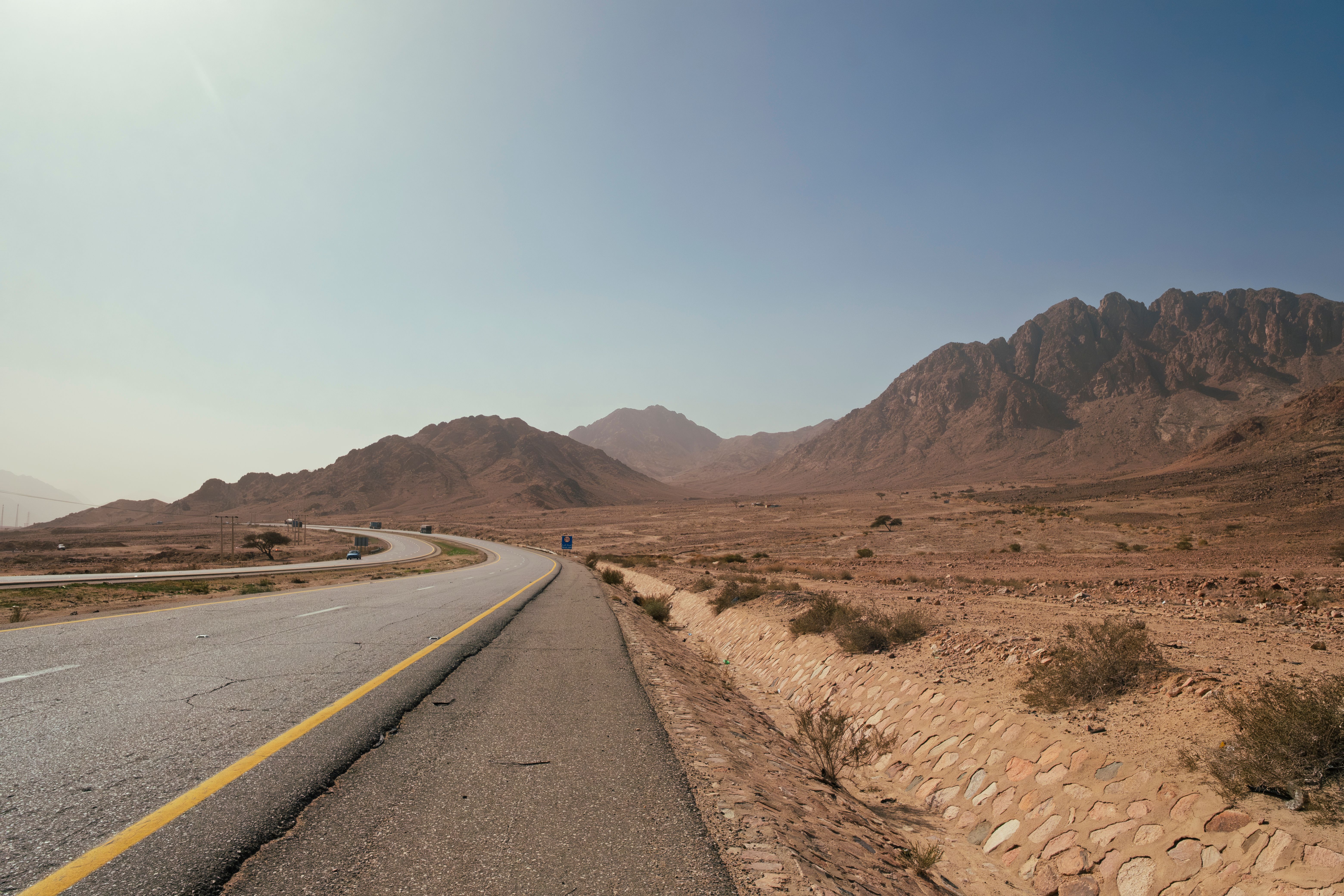 A car driving on the scenic King's Highway in Jordan, winding through mountains.