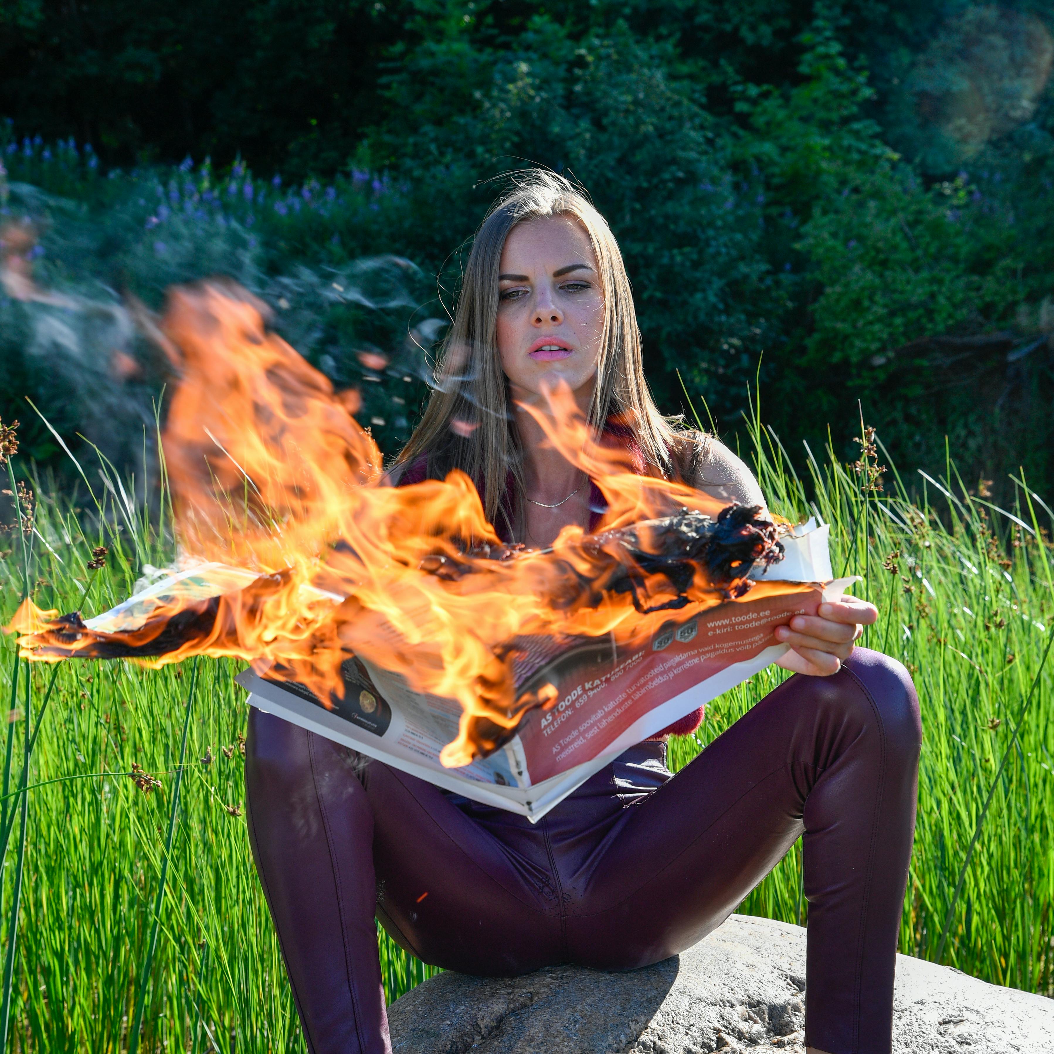 Gratis Foto drammatica di una donna che legge un giornale in fiamme all'aperto in Estonia. Foto a disposizione
