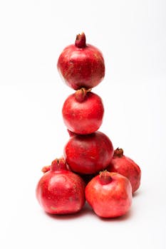 A creative stack of fresh red pomegranates on a white background, perfect for food and health themes.