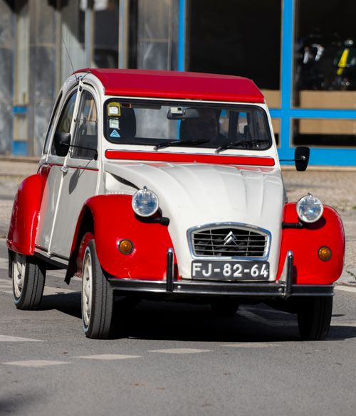 Free Vintage red and white Citroën 2CV driving through Olhão, Portugal street. Stock Photo