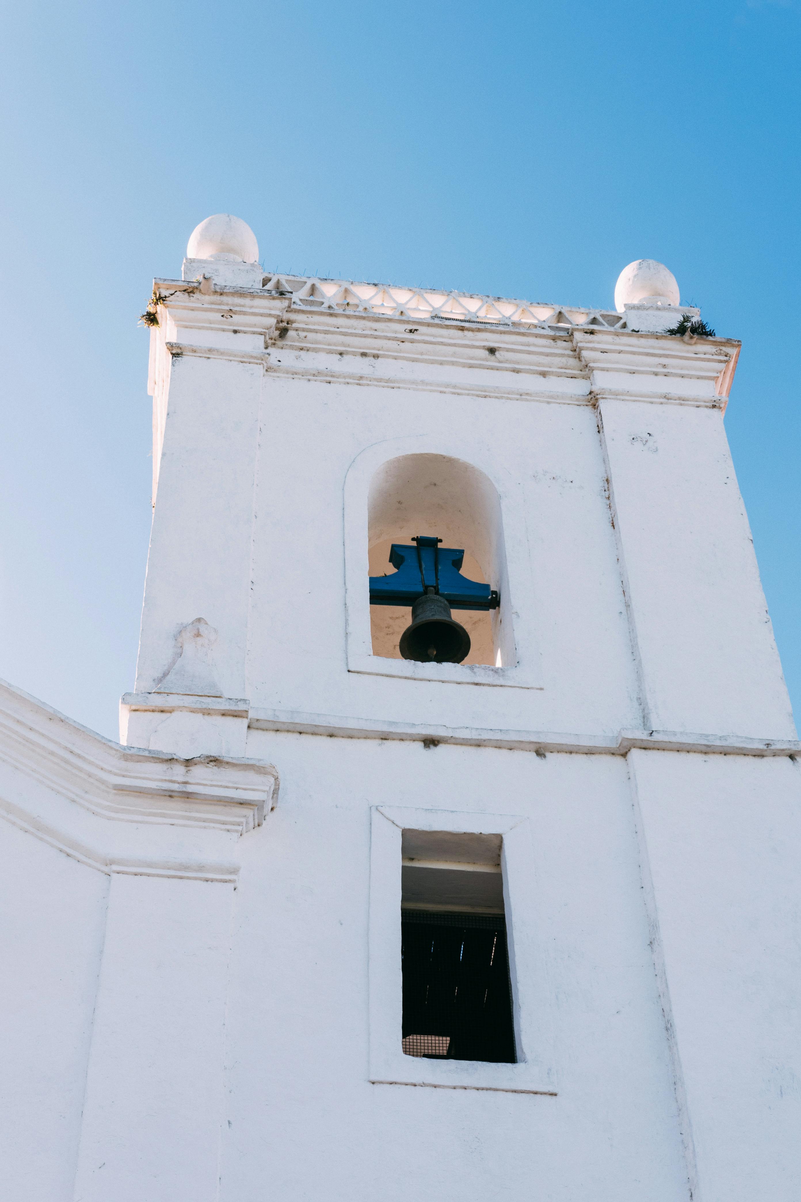 Gratuit Gros plan sur le clocher blanc d'une église se détachant sur un ciel bleu clair. Photos