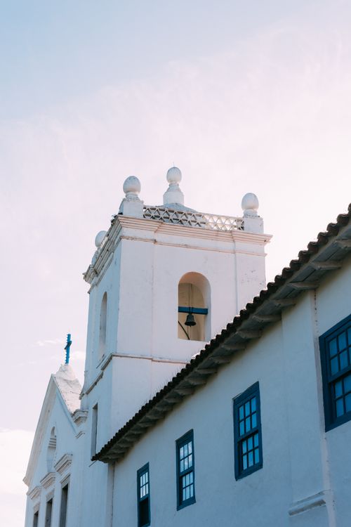 Free A picturesque white church tower with a bell, under a clear blue sky, in a serene setting. Stock Photo