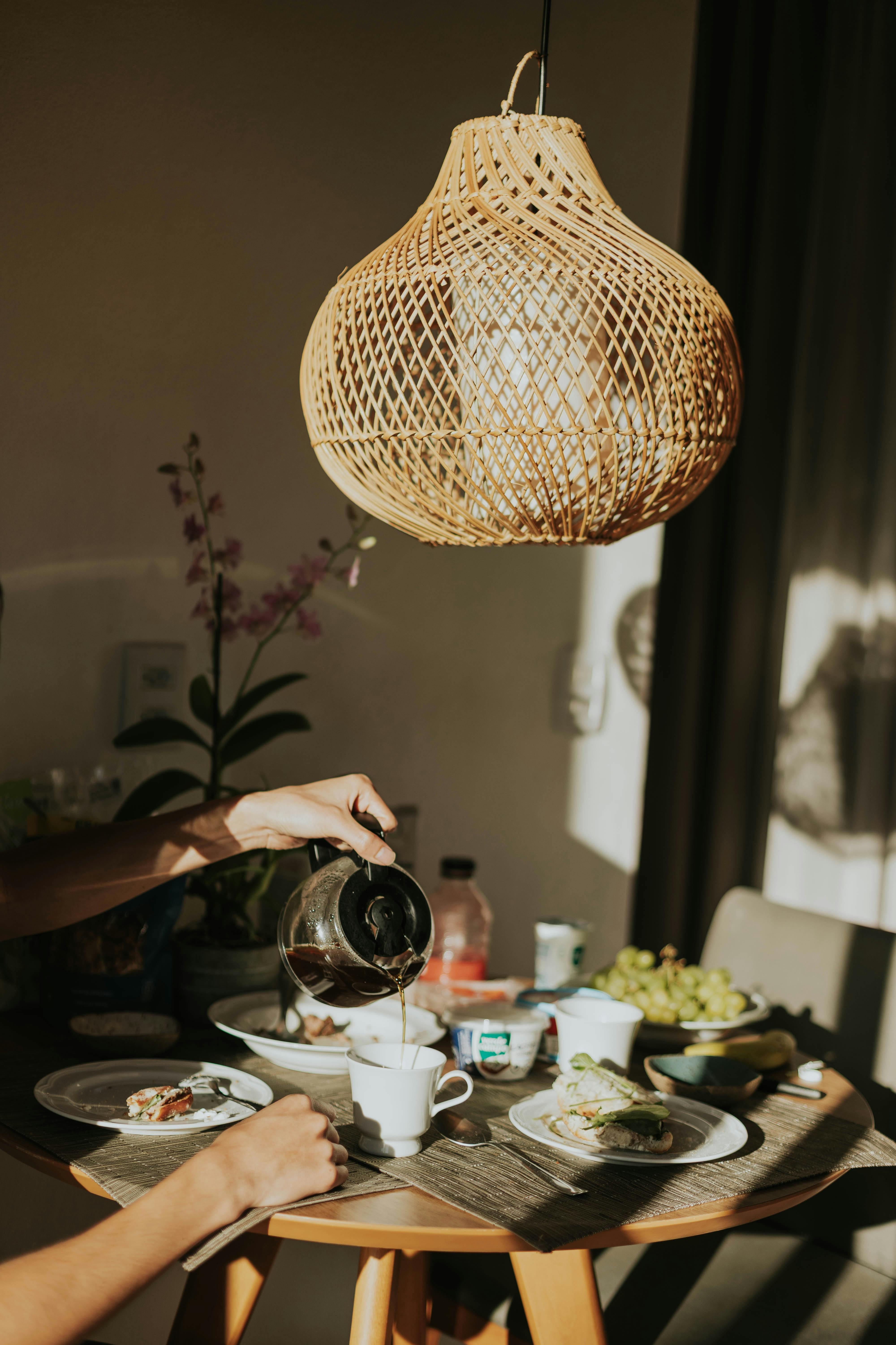 ฟรี ภาพบรรยากาศอบอุ่นภายในห้องรับประทานอาหารเช้า มีกาแฟกำลังเท และแสงธรรมชาติส่องเข้ามา คลังภาพถ่าย