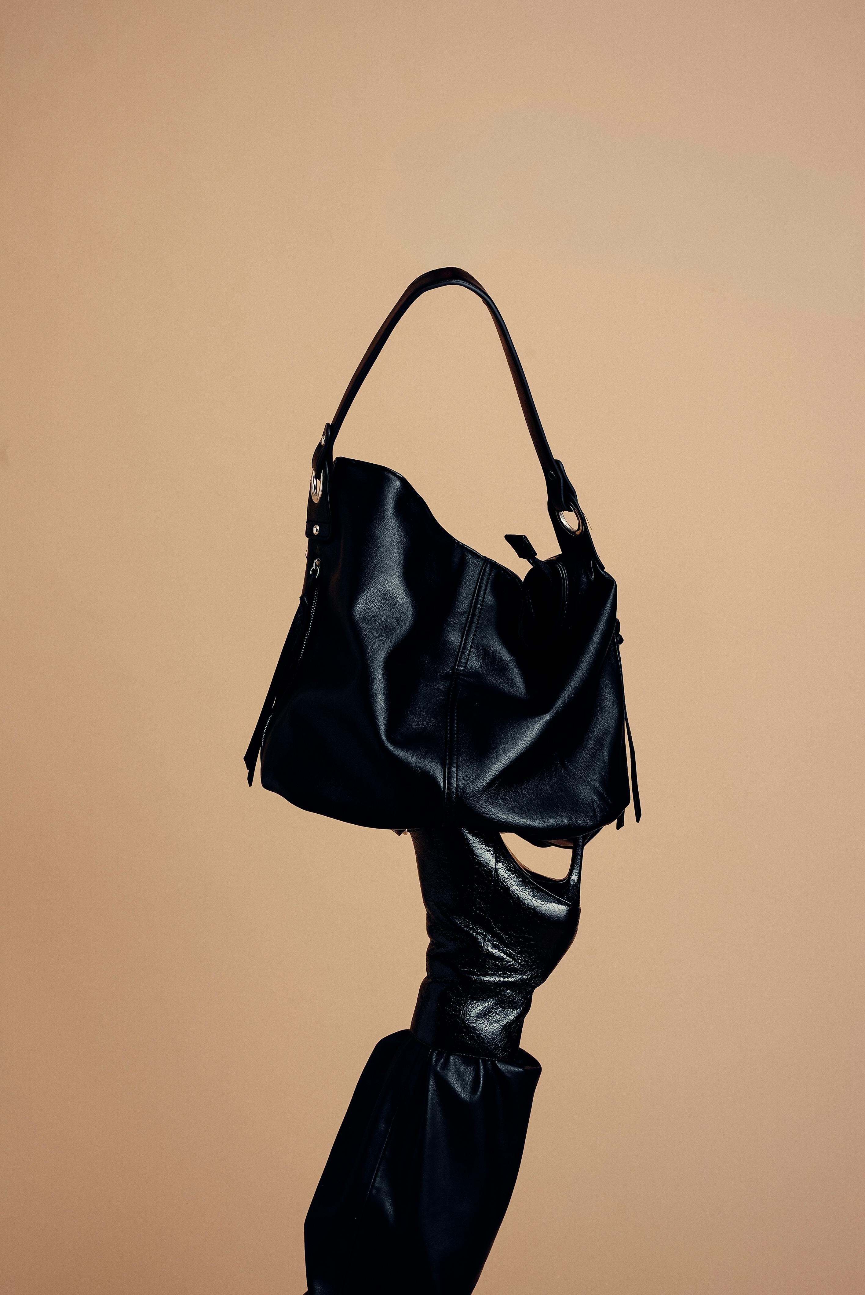 Free A modern black leather handbag elegantly displayed on a stylish, artistic stand against a neutral background. Stock Photo