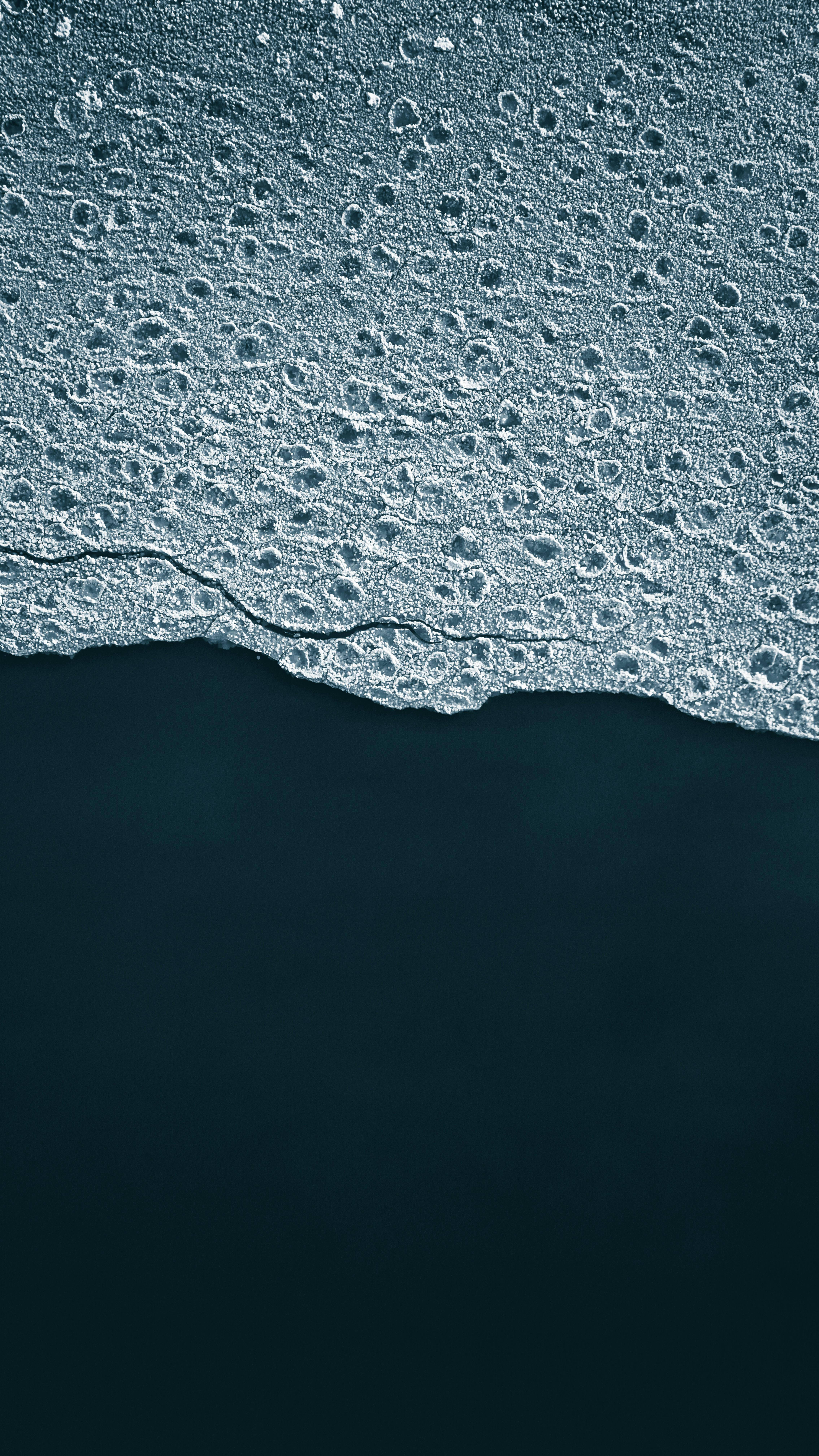 Gratis Vista aerea del bordo del ghiaccio strutturato sullo sfondo dell'acqua scura, che mette in mostra la bellezza invernale. Foto a disposizione