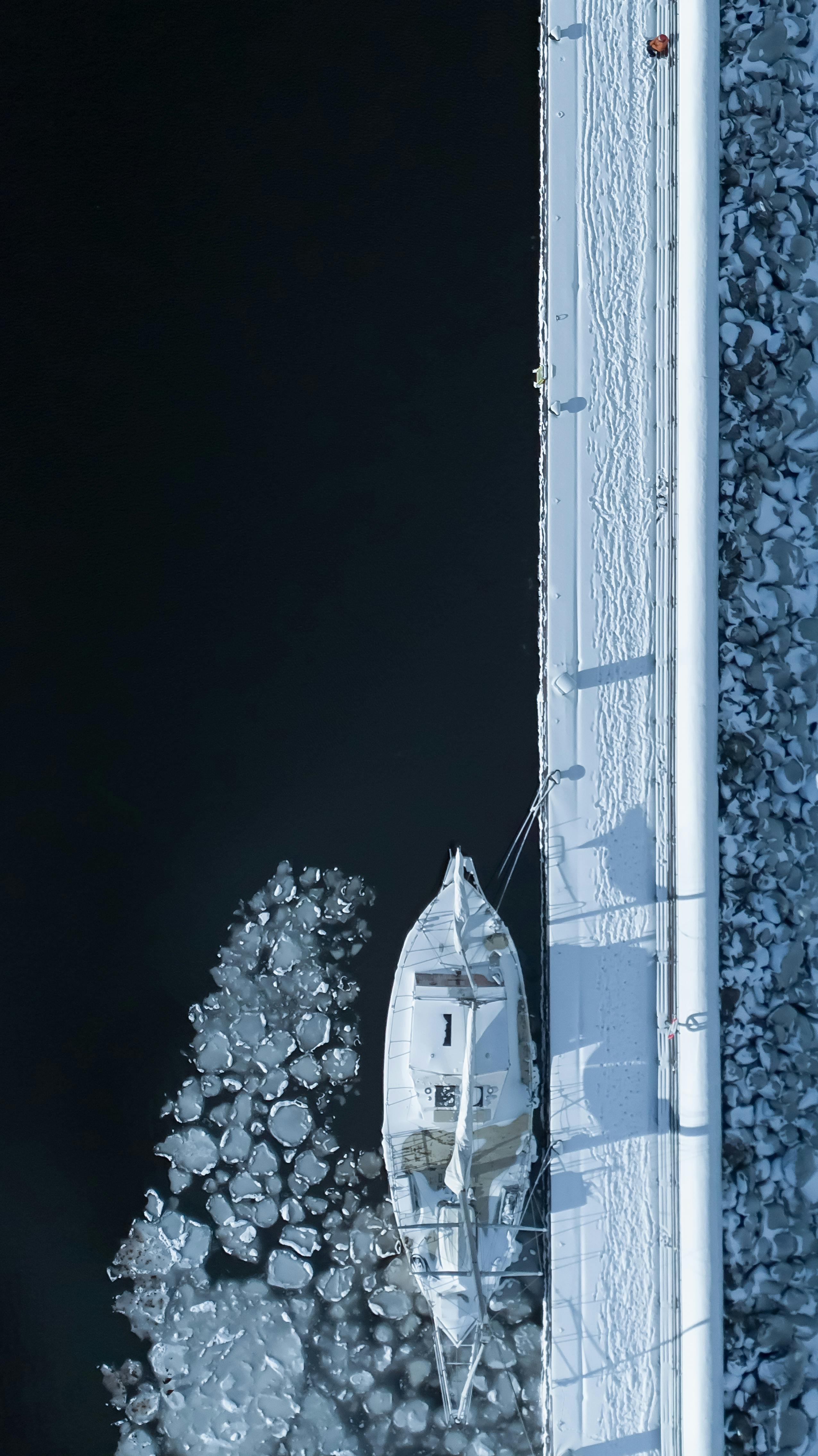 Ücretsiz İsveç'in Jönköping kentinde, karla kaplı bir iskeleye bağlı bir teknenin drone ile çekilmiş görüntüsü. Stok Fotoğraflar