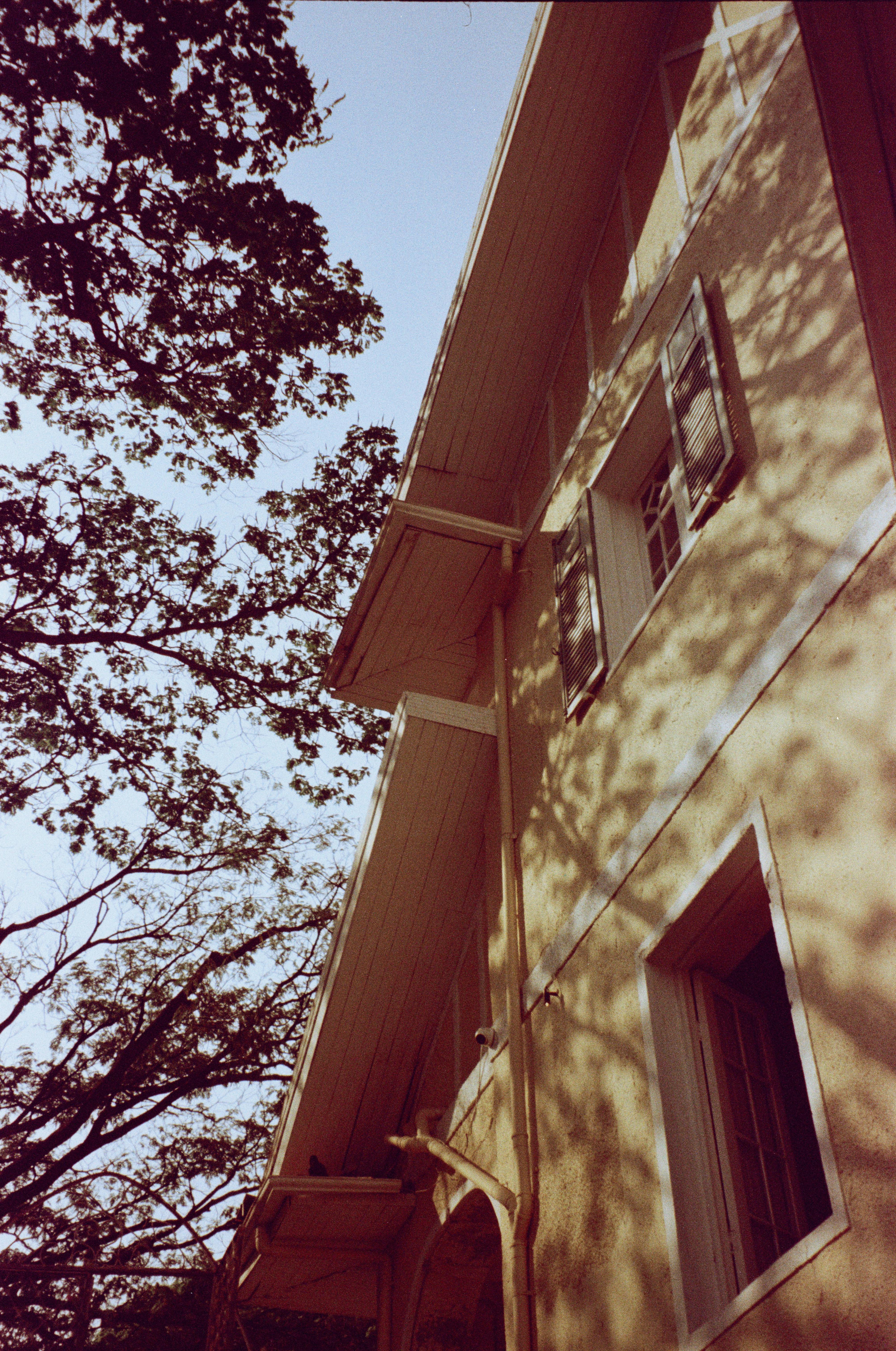 Zadarmo Exteriér vintage domu so zelenými okenicami a tieňmi stromov, ktoré umocňujú jeho klasický vzhľad. Fotka z fotobanky