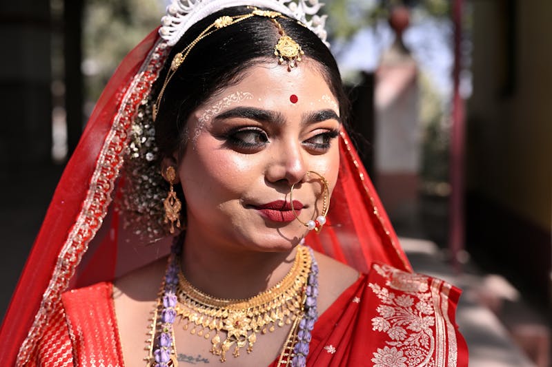 A stunning Bengali bride in red attire with intricate jewelry capturing a moment of elegance.