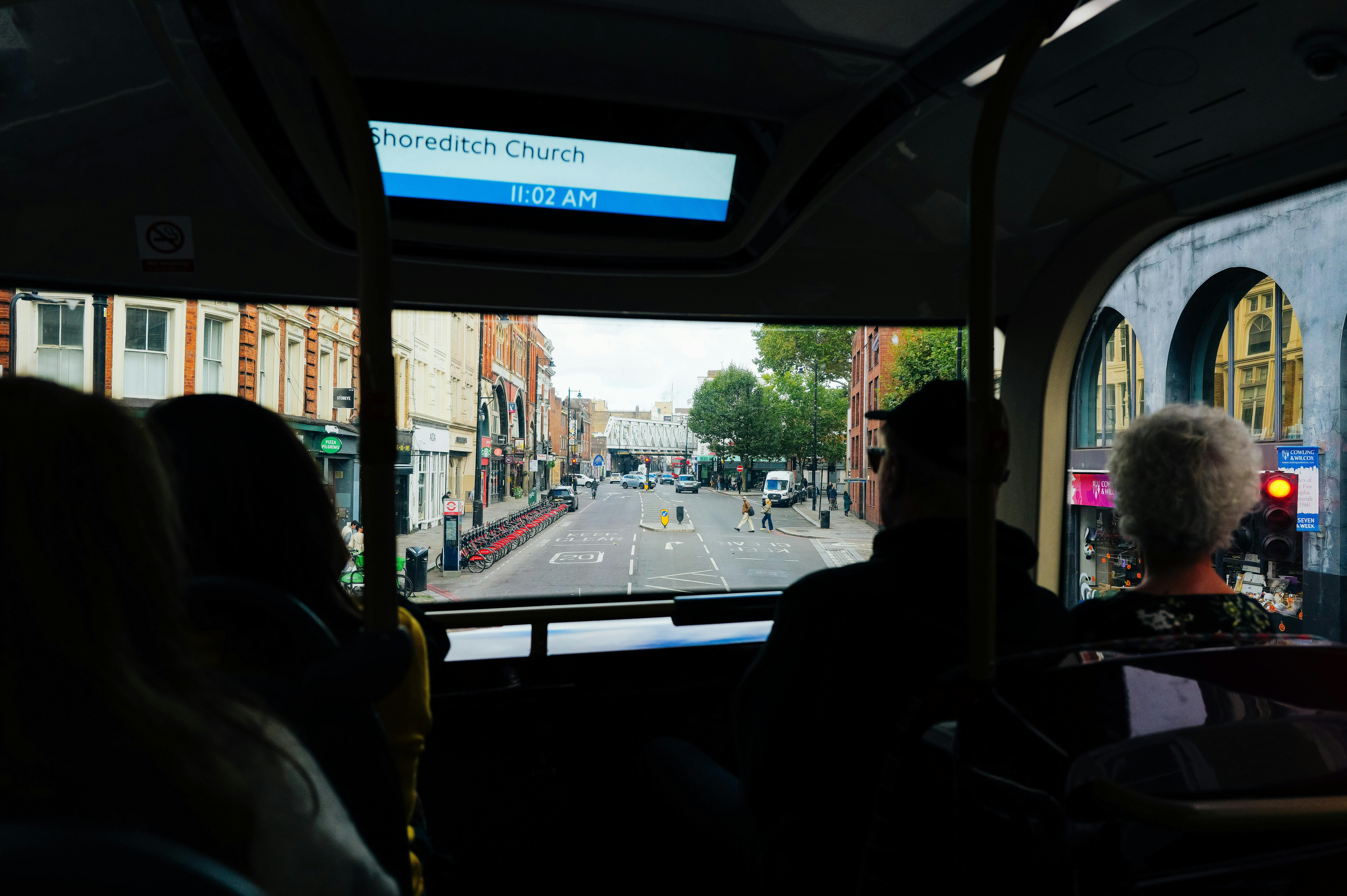 People enjoying city view from bus in Shoreditch London, showing urban scene.