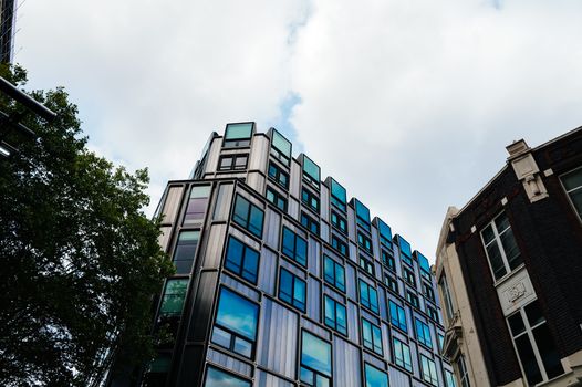 A contemporary building with reflective windows in an urban setting under a cloudy sky.