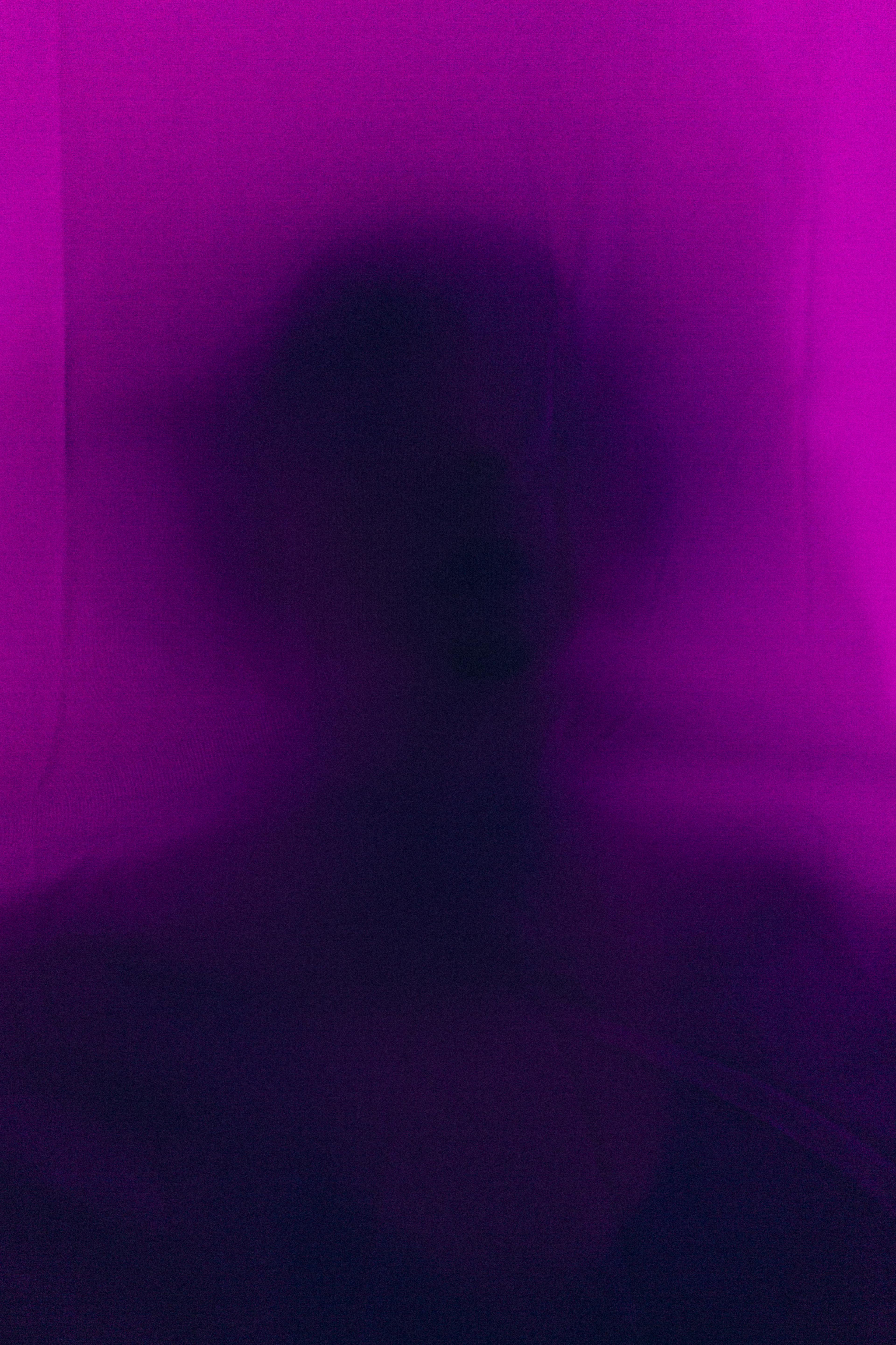 Artistic silhouette of a person blurred behind purple fabric, creating a mysterious effect.
