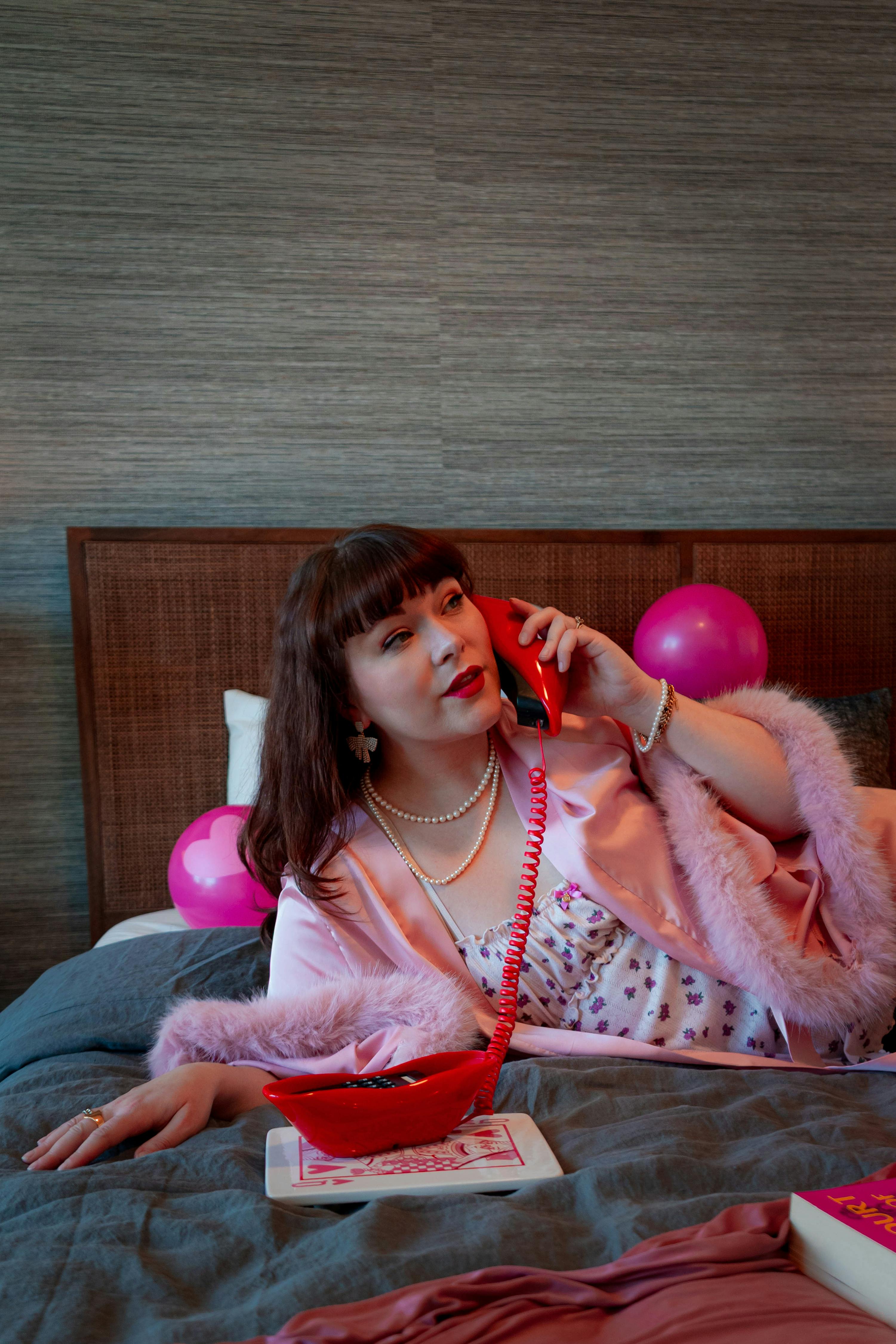 gratis Elegante vrouw in roze badjas met vintage telefoon en decoratie in een huiselijke omgeving. Stockfoto