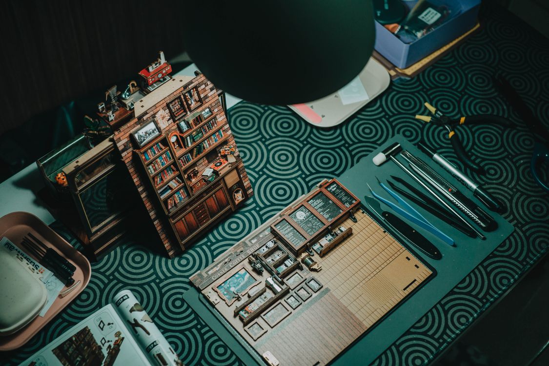 Miniature bookshelf crafting setup with tiny handmade books and small tools on a craft table