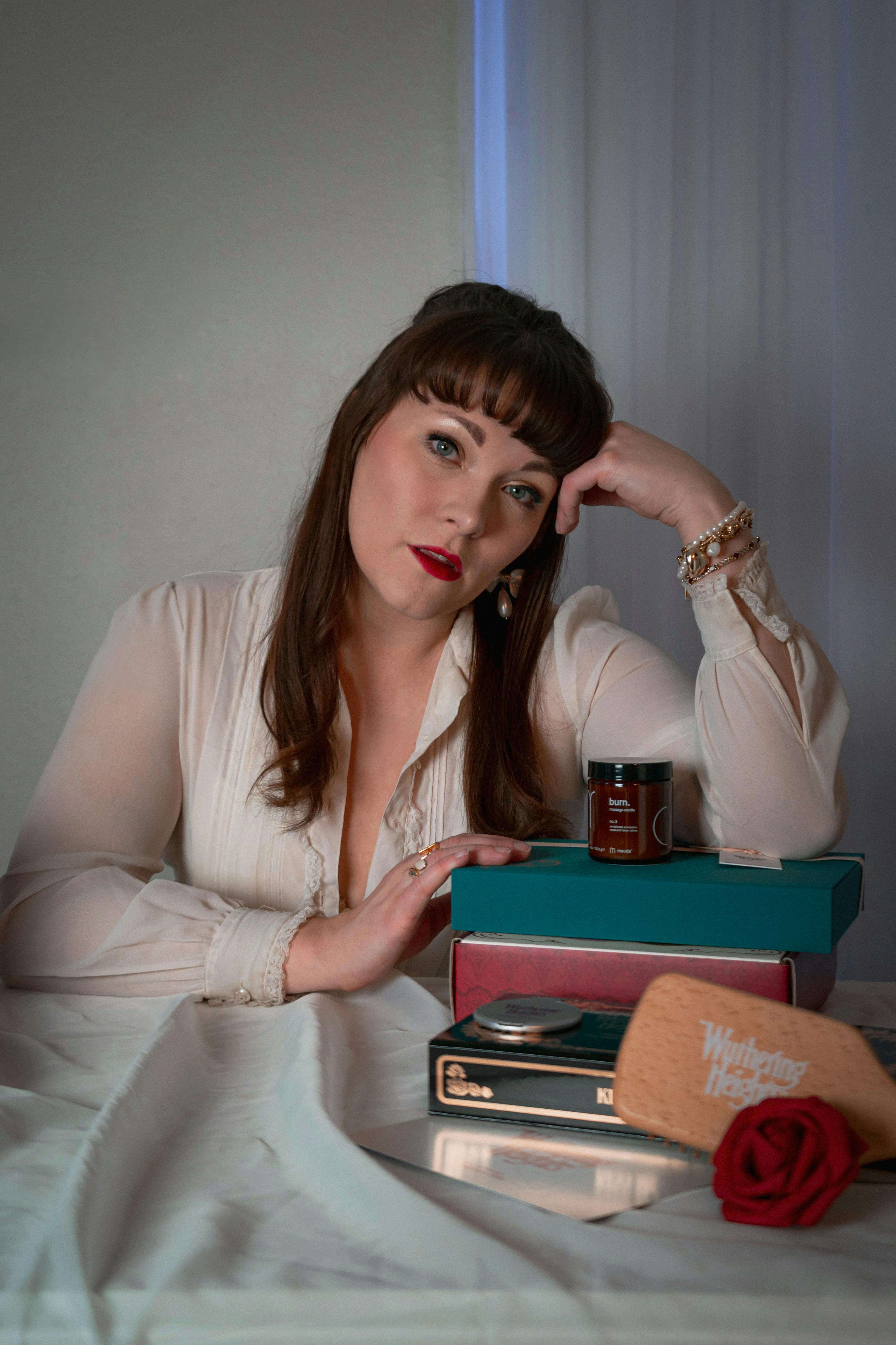 ฟรี ภาพถ่ายสร้างสรรค์ของหญิงสาวในสไตล์วินเทจรายล้อมไปด้วยหนังสือและดอกกุหลาบภายในบ้าน คลังภาพถ่าย