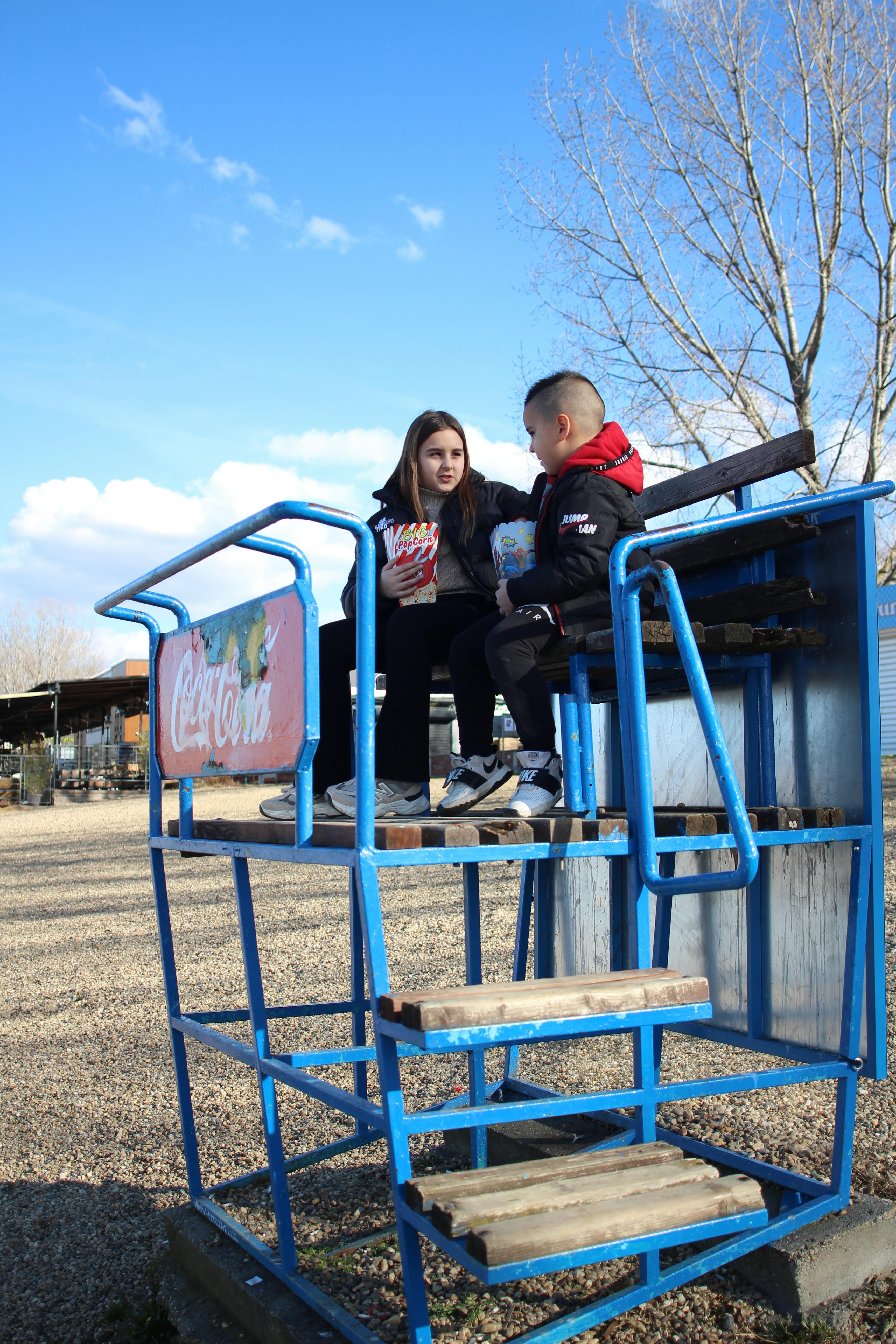 Gratuit Deux enfants prennent un goûter sur une structure en bois, dans un cadre extérieur ensoleillé. Photos