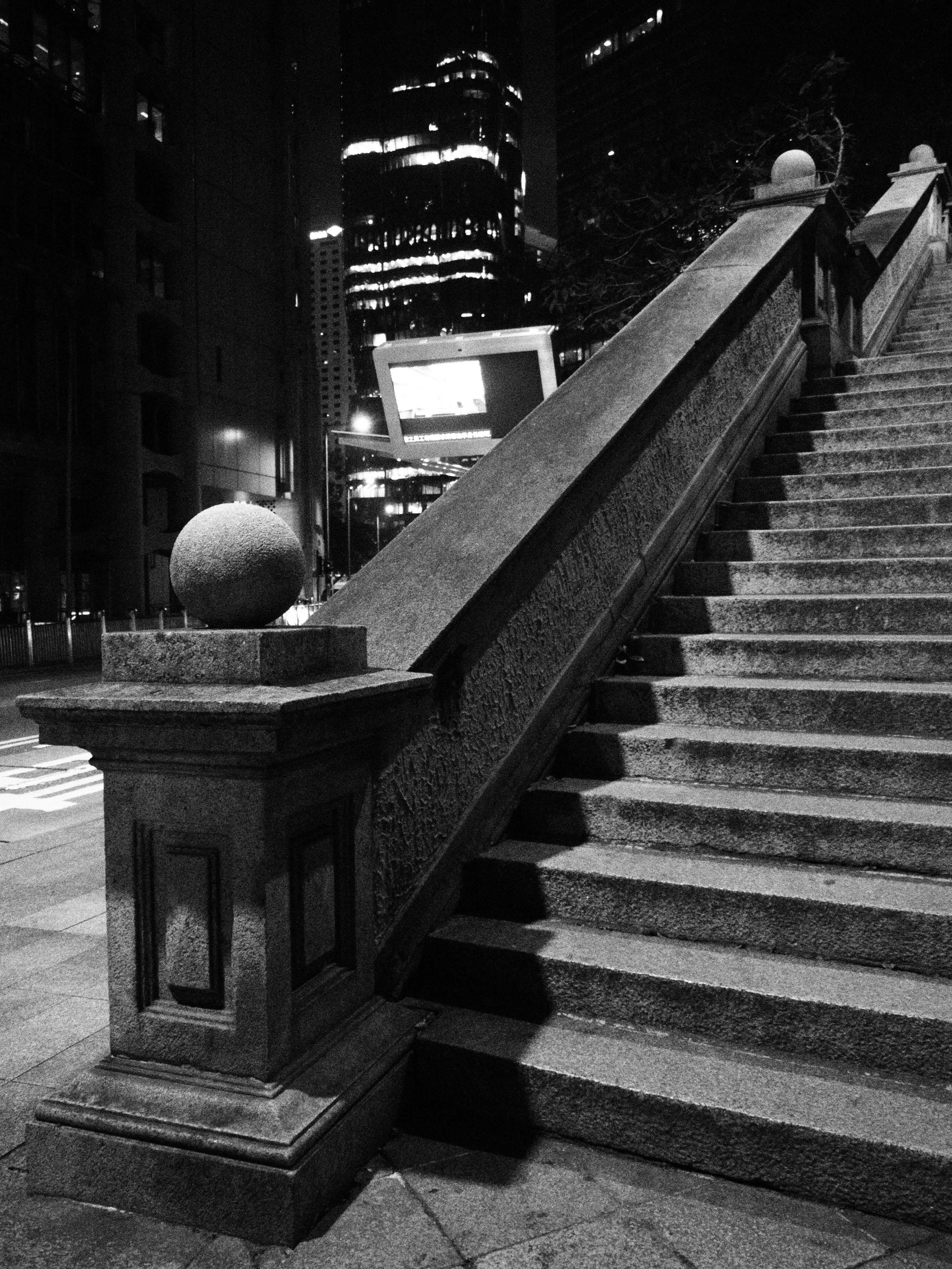 Kostnadsfria Elegant svartvitt foto av en stentrappa med stadsljus i Hongkong på natten. Stock foto