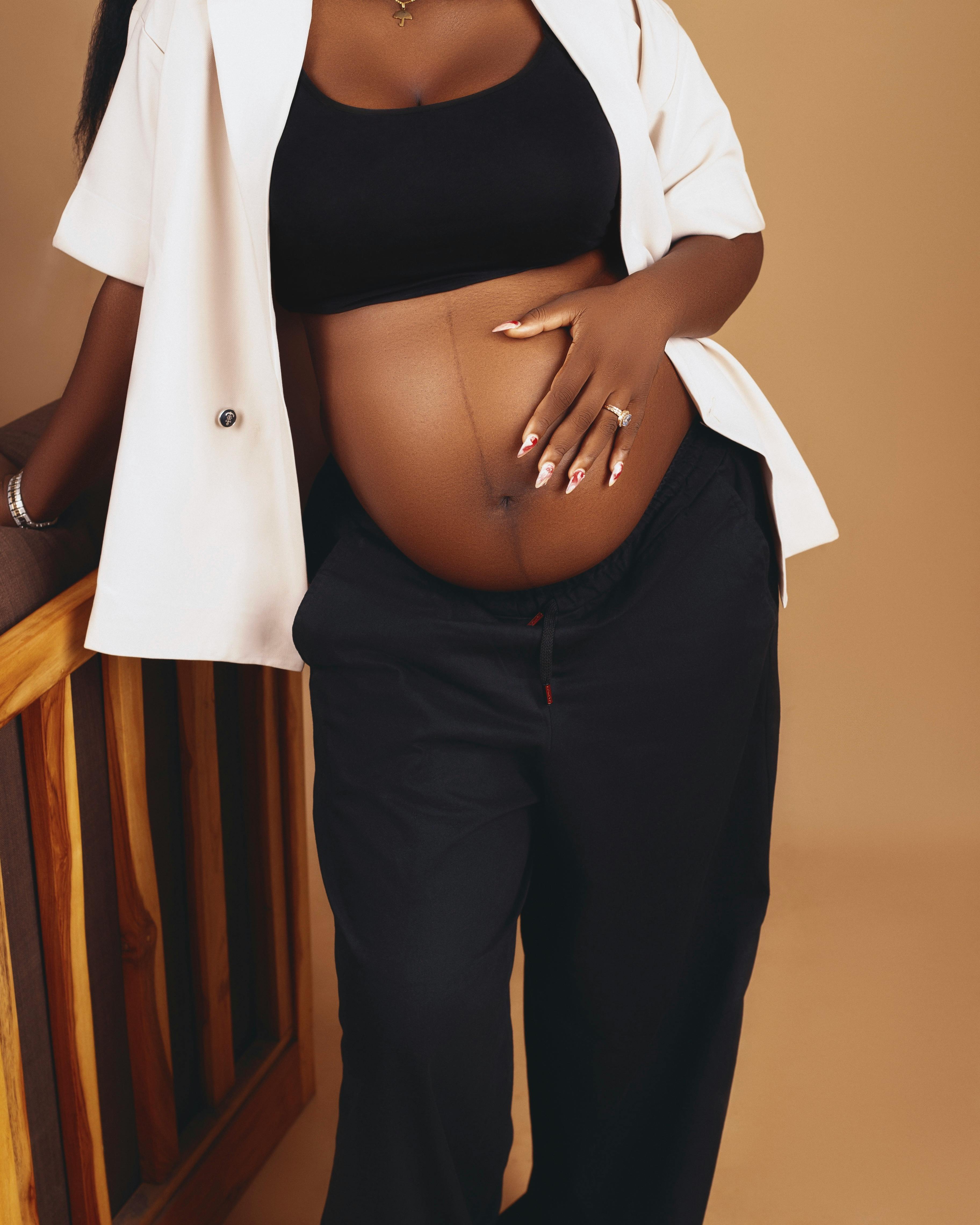 Free A fashionable pregnant woman cradling her belly indoors in Abuja, Nigeria. Stock Photo