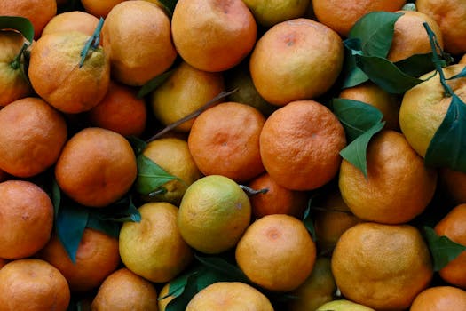 A vibrant collection of fresh tangerines with green leaves, showcasing citrus fruit abundance.