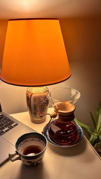 Warm indoor scene of a coffee setup with a brewhouse and lamp, perfect for relaxation.