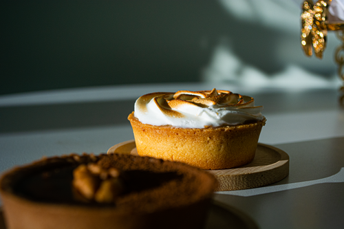 Free Delicious meringue tart with rich chocolate filling, highlighted by natural sunlight for an artistic culinary presentation. Stock Photo