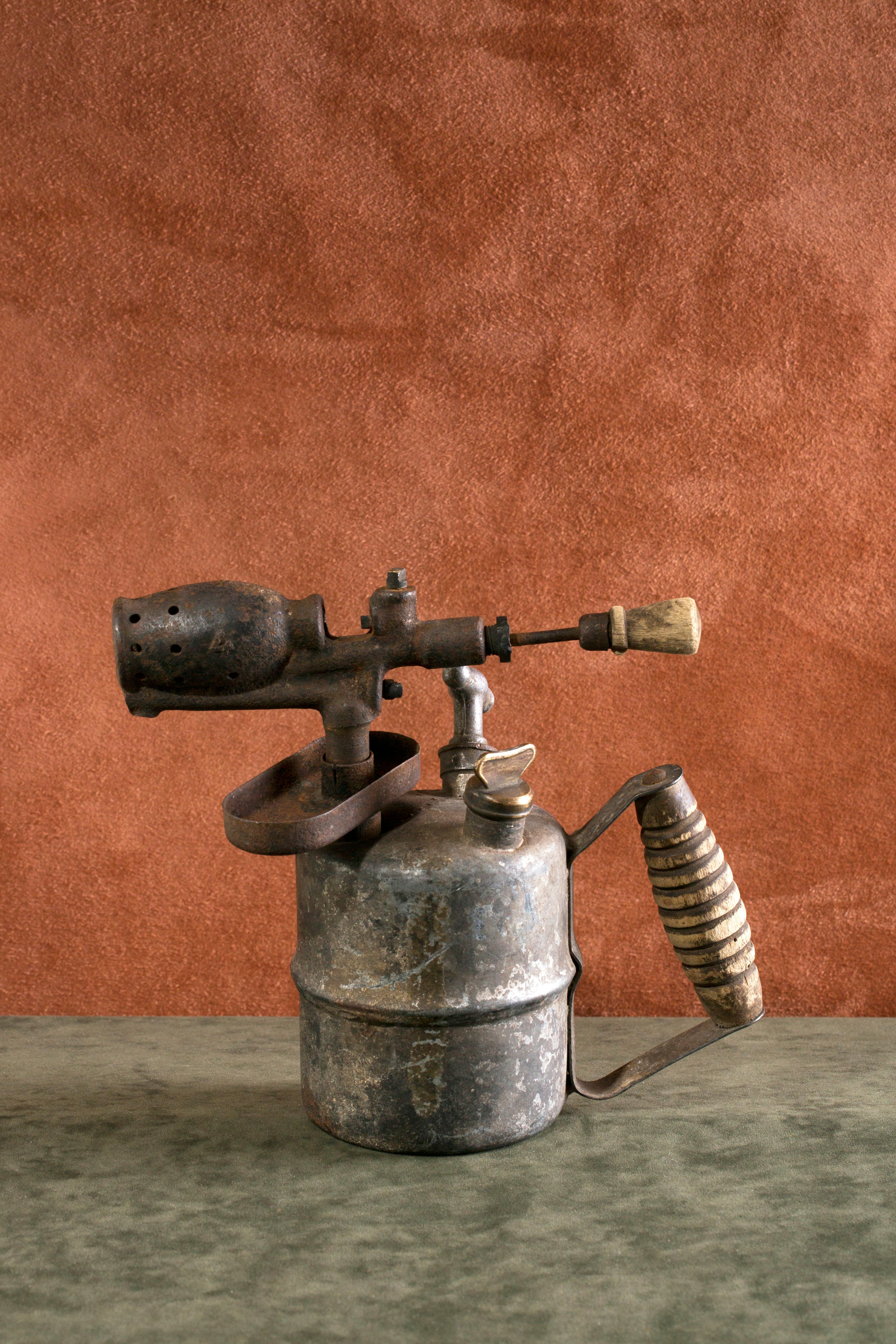 Free Rustic vintage blowtorch with wooden handle on textured orange backdrop. Stock Photo
