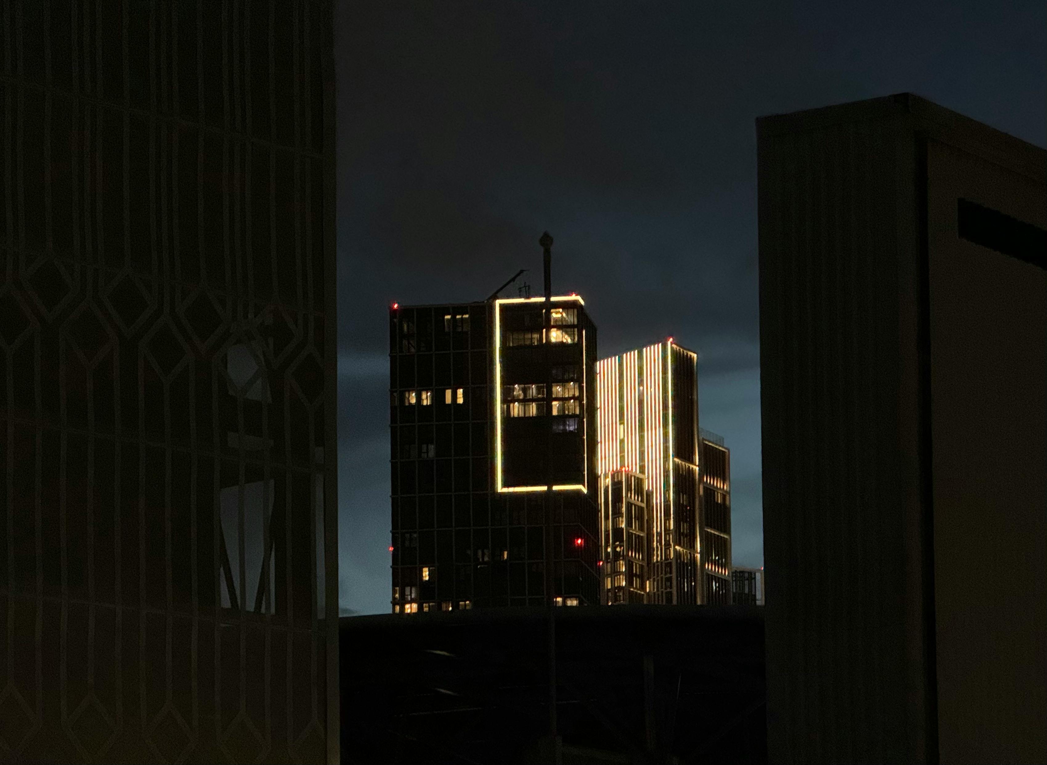 Kostnadsfria Dramatisk vy av skyskrapor med glödande konturer i skymningen, som kastar en unik urban silhuett. Stock foto