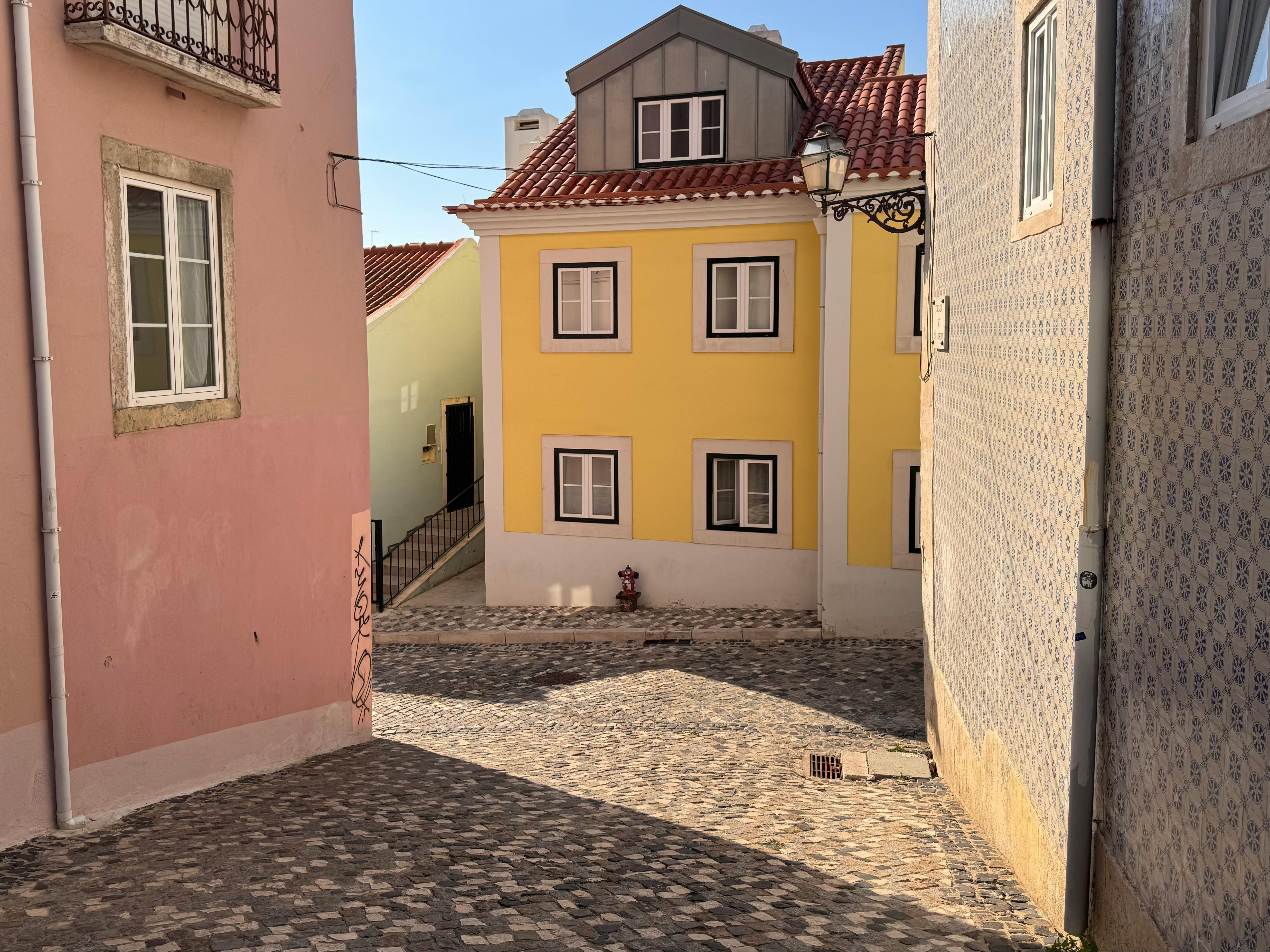 A charming, narrow historic alleyway in a European town, adorned with blooming flowers, traditional architecture, and soft streetlights.