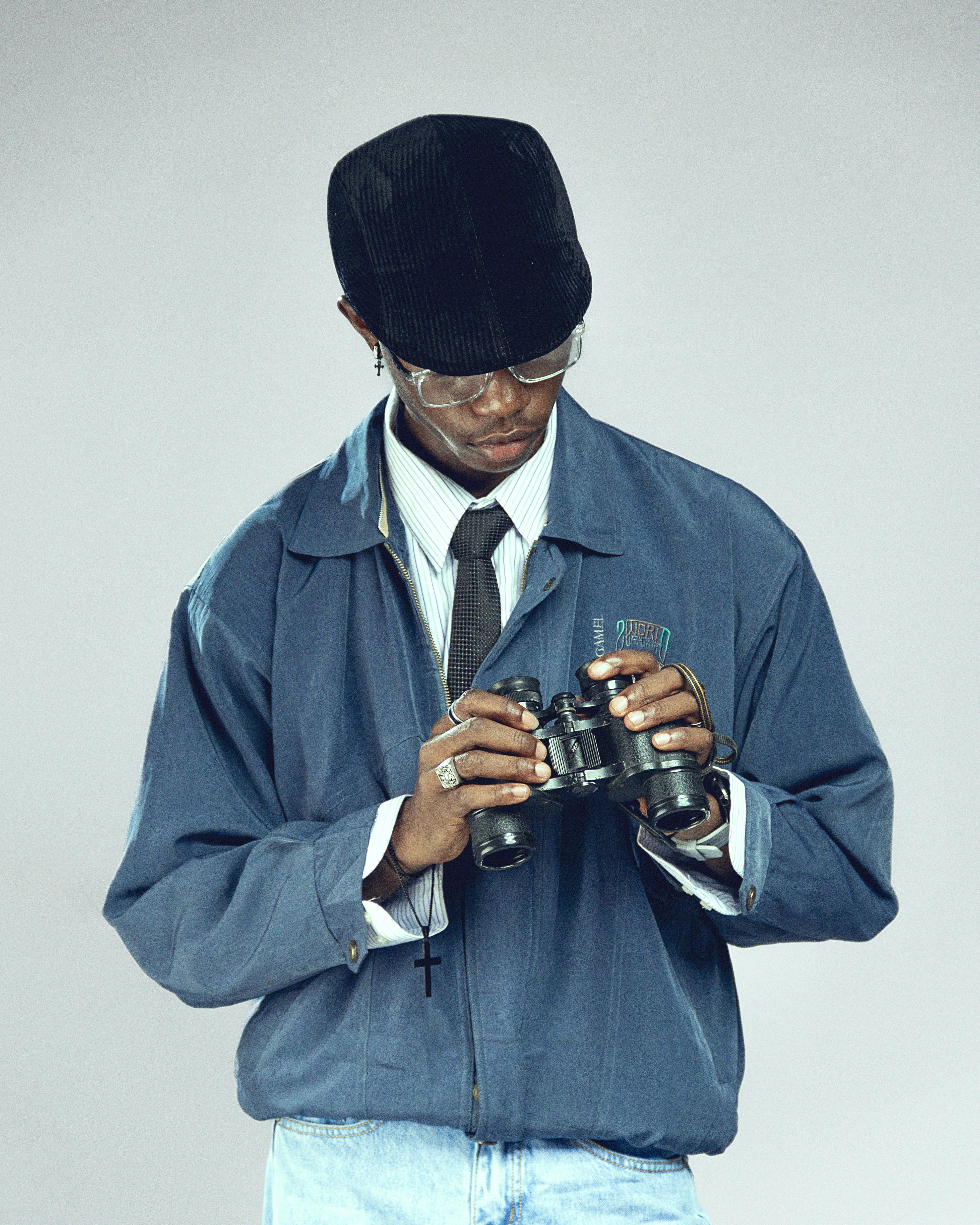 Miễn phí Một chàng trai trẻ trong trang phục cổ điển đang chăm chú quan sát ống nhòm với vẻ mặt tập trung. Ảnh lưu trữ