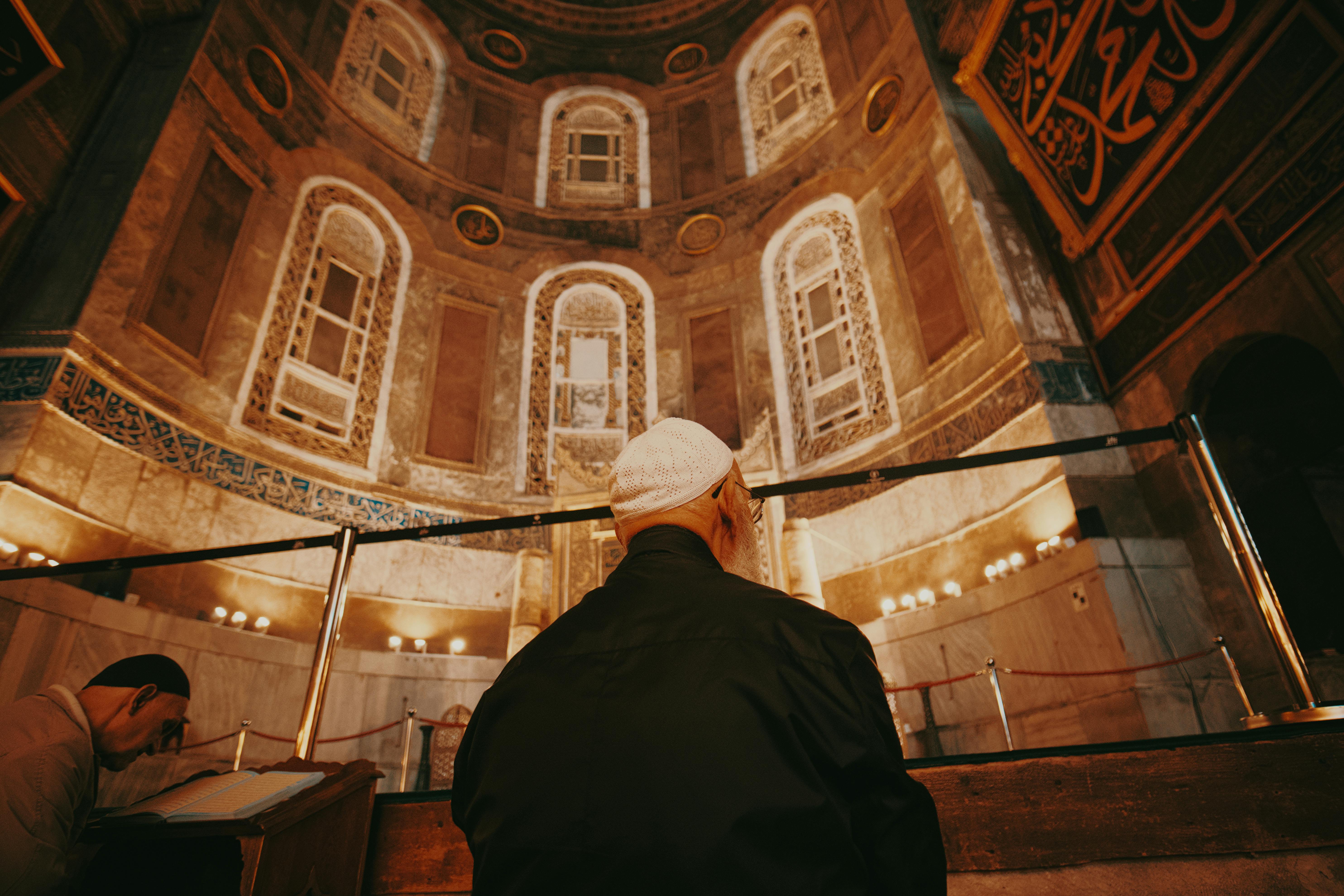 Kostenlos Ein Mann in traditioneller Kleidung betet in einer prachtvoll geschmückten historischen Moschee. Stock-Foto