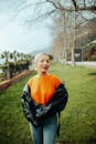 Woman in Orange Sweater on a Grass Path