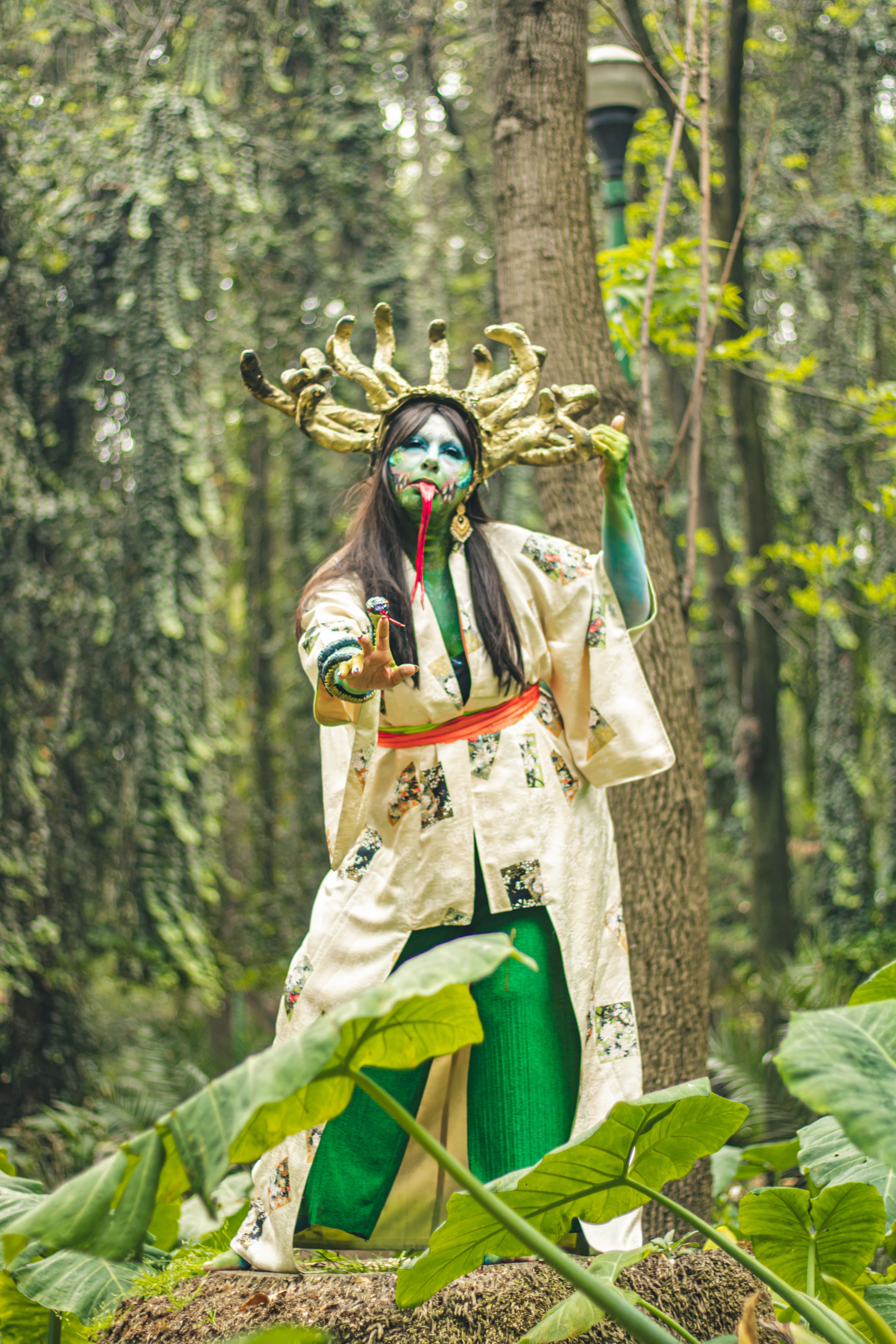 Fantasy cosplay character in nature with vibrant makeup and cultural attire.