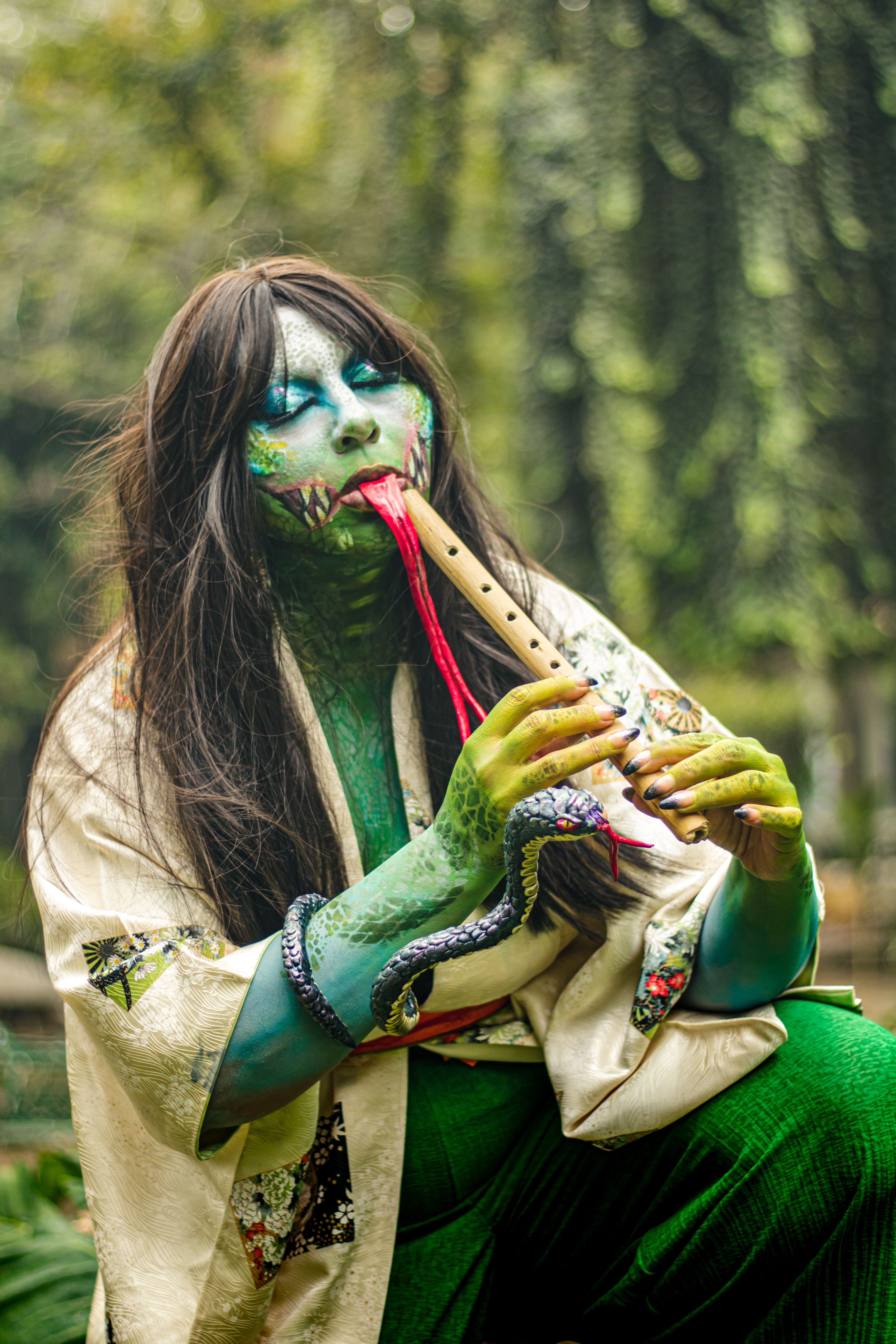 Cosplayer in Gorgona makeup plays a flute in a vibrant, artistic outdoor setting.