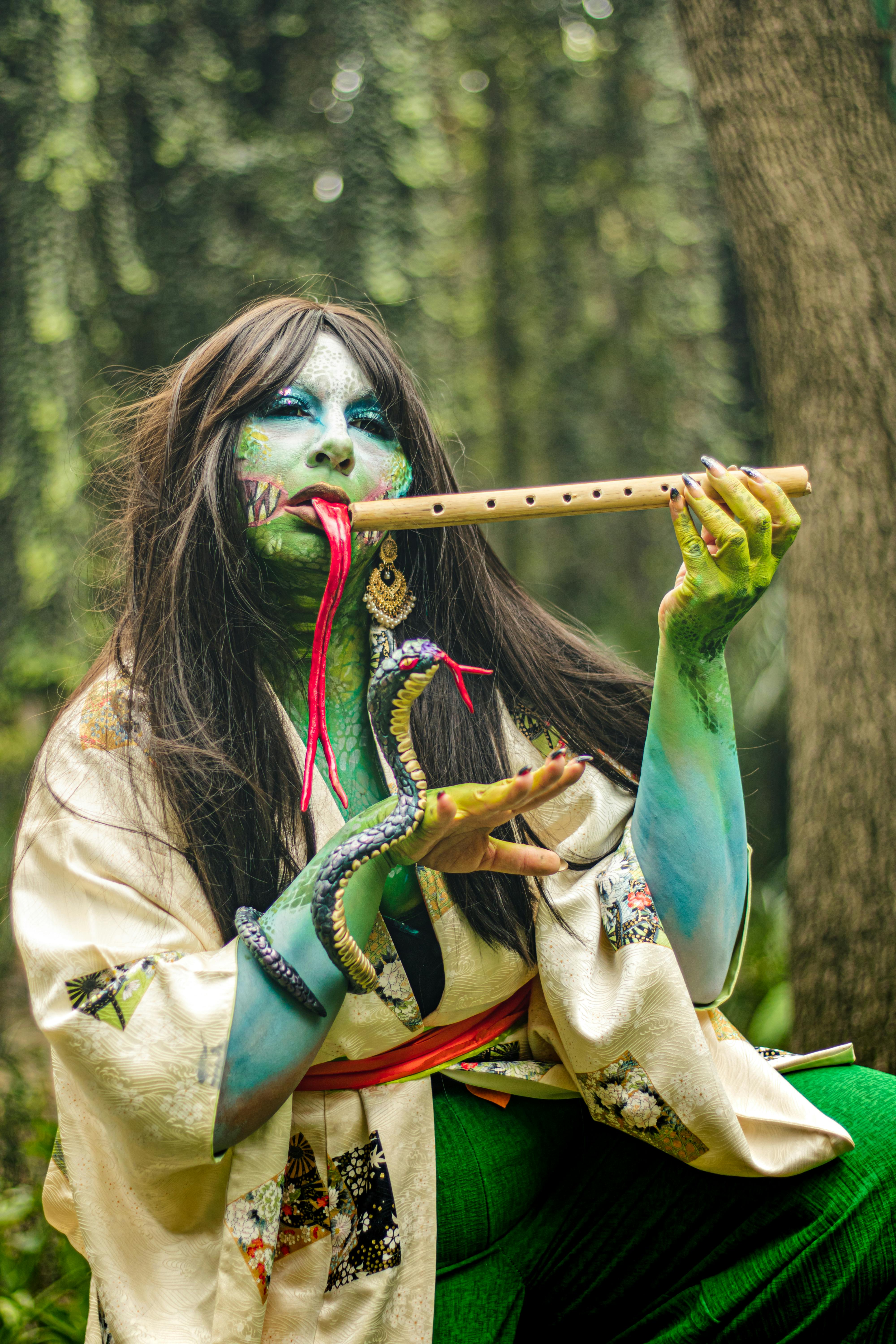Creative cosplay with vibrant makeup and a snake prop in a forest setting.