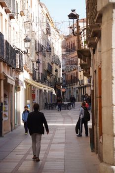 A picturesque pedestrian street in Ávila, Spain with people enjoying a sunny day.