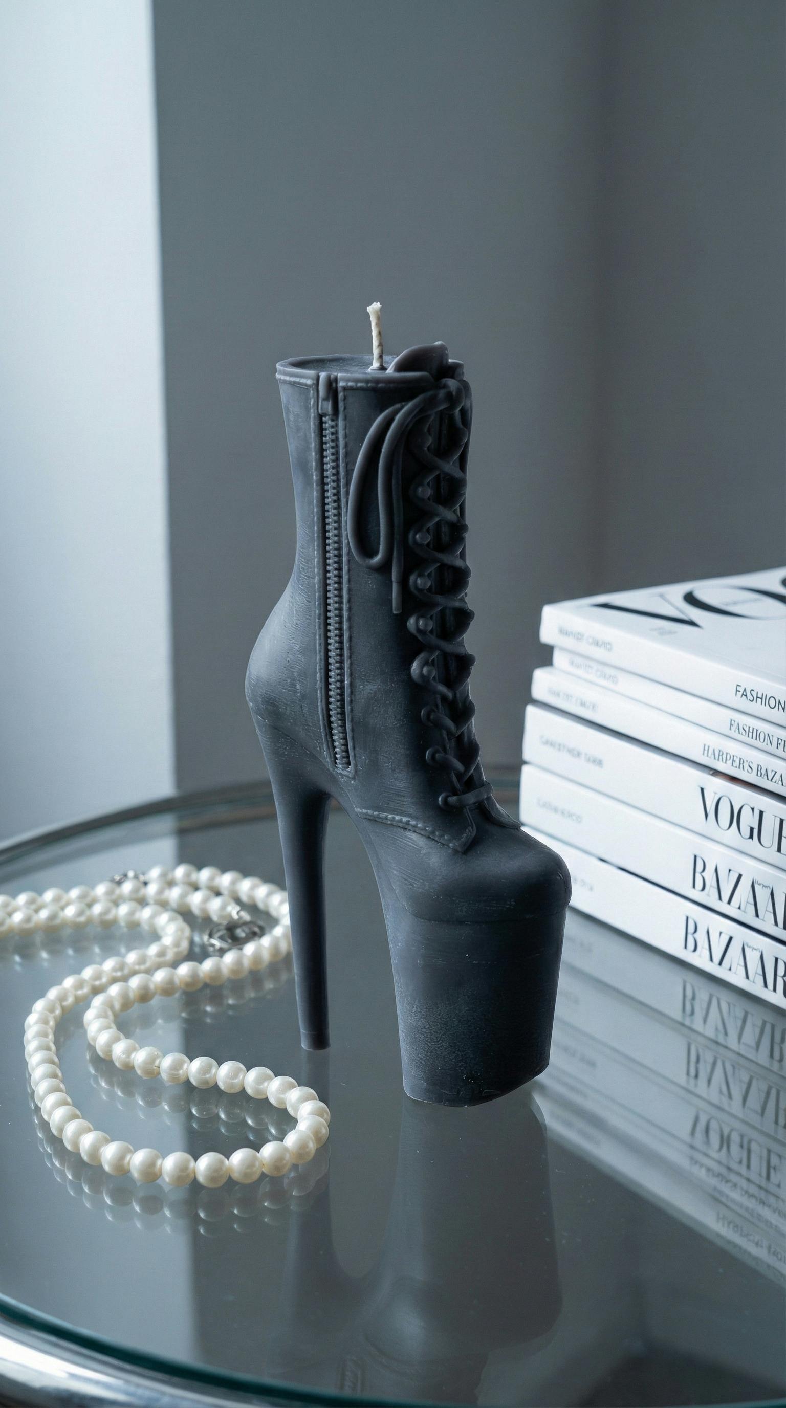 De franc Espelma negra de taló alt amb collaret de perles sobre taula, decoració moderna. Foto d'estoc