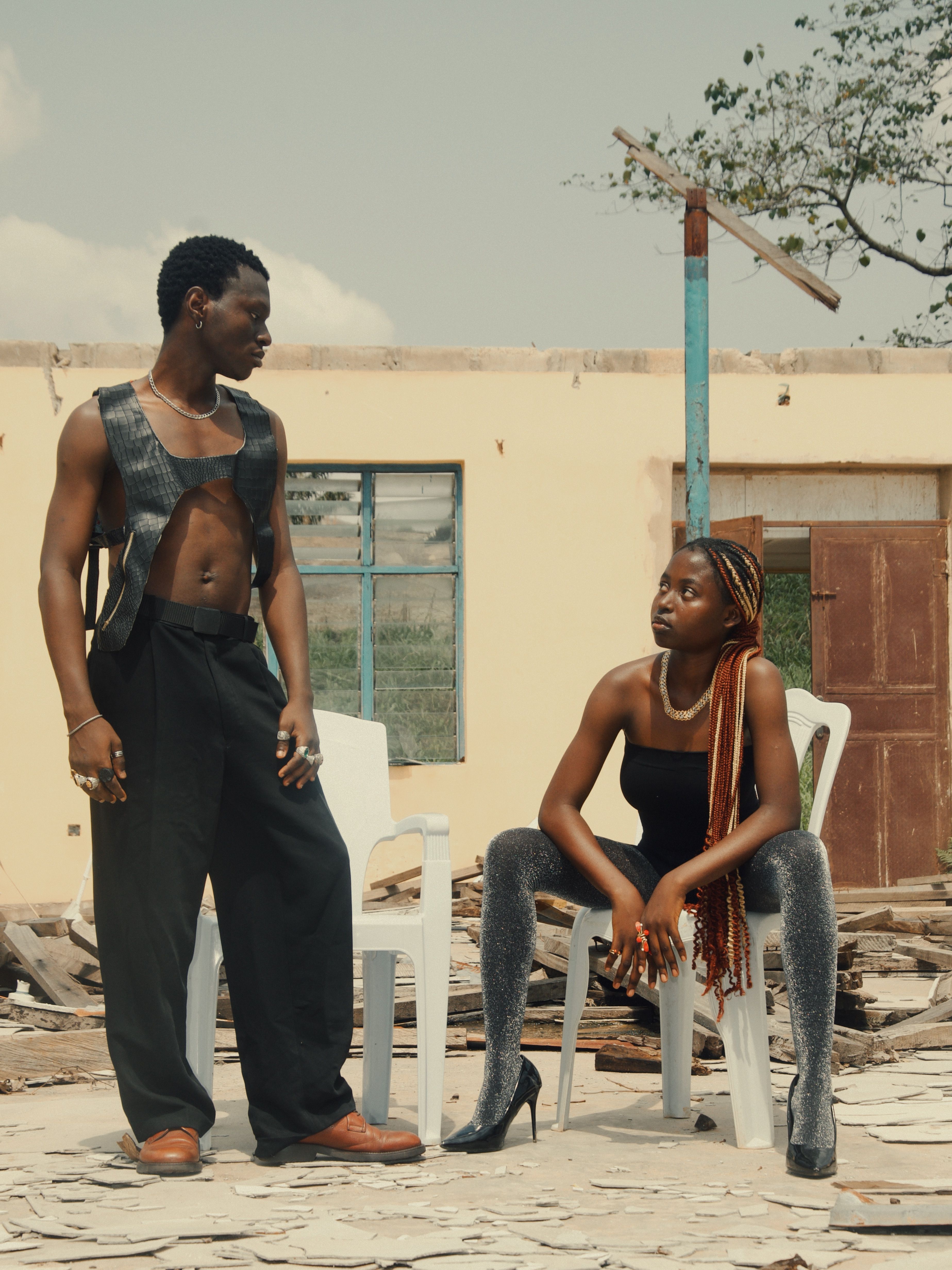 Stylish duo posing outdoors with urban backdrop, showcasing modern fashion.