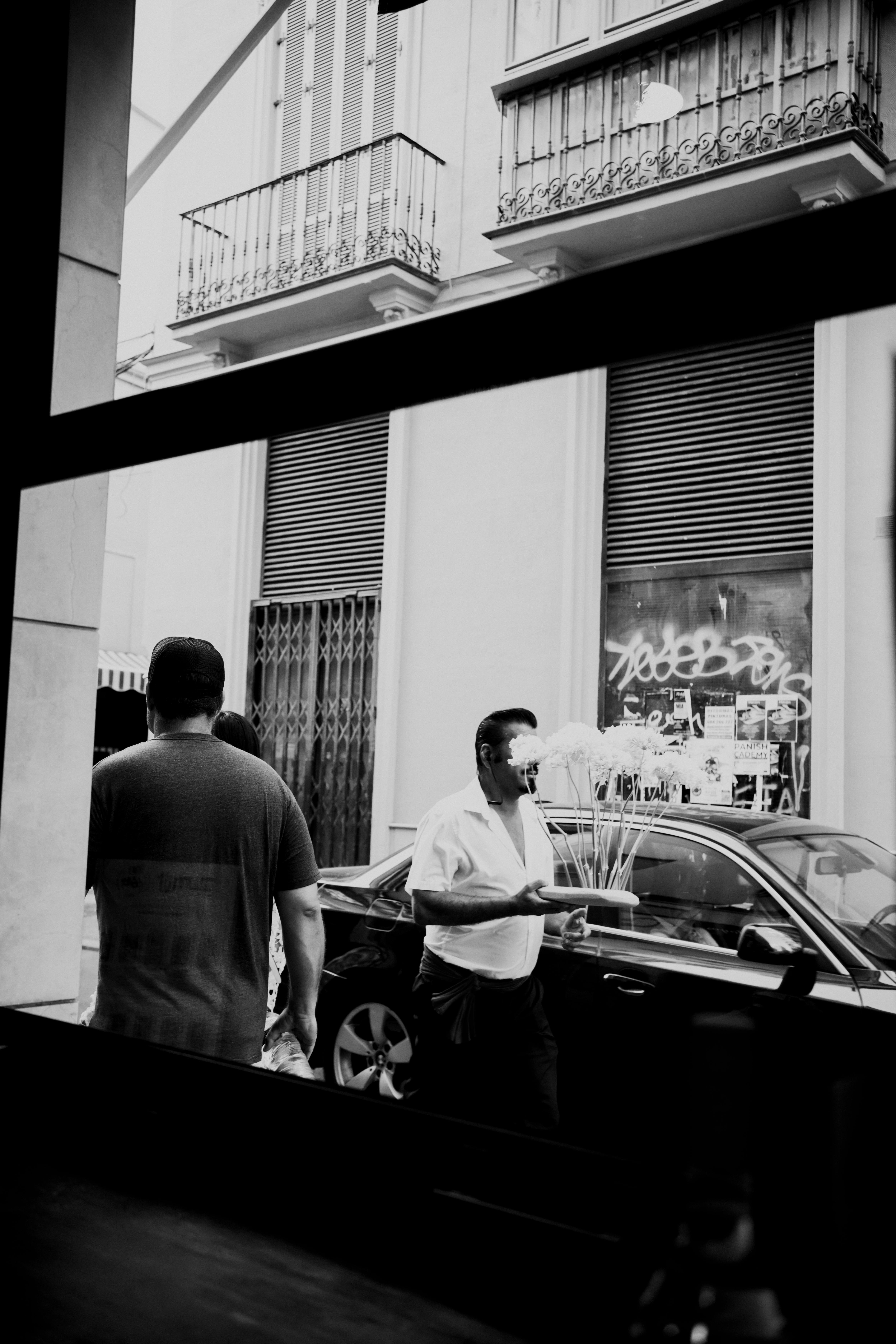 Gratuit Scenă stradală sinceră alb-negru, privită printr-o fereastră, cu oameni mergând. Fotografie de stoc