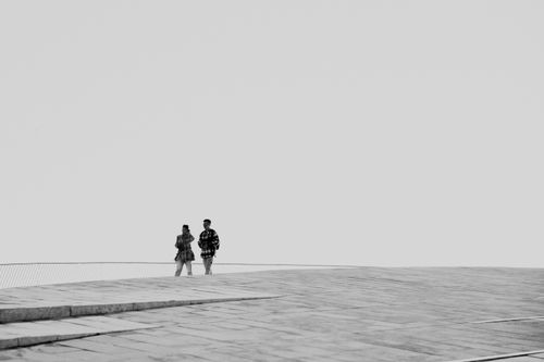 Free Two people walking on a modern architectural structure under a clear sky. Stock Photo