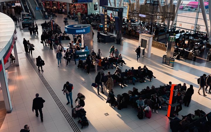 A bustling airport terminal with travelers waiting and moving through the space.