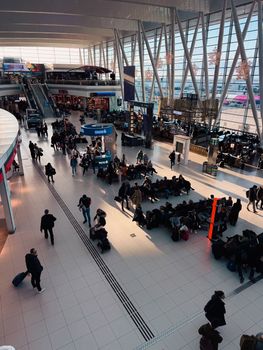 A bustling airport terminal with travelers waiting and moving through the space.