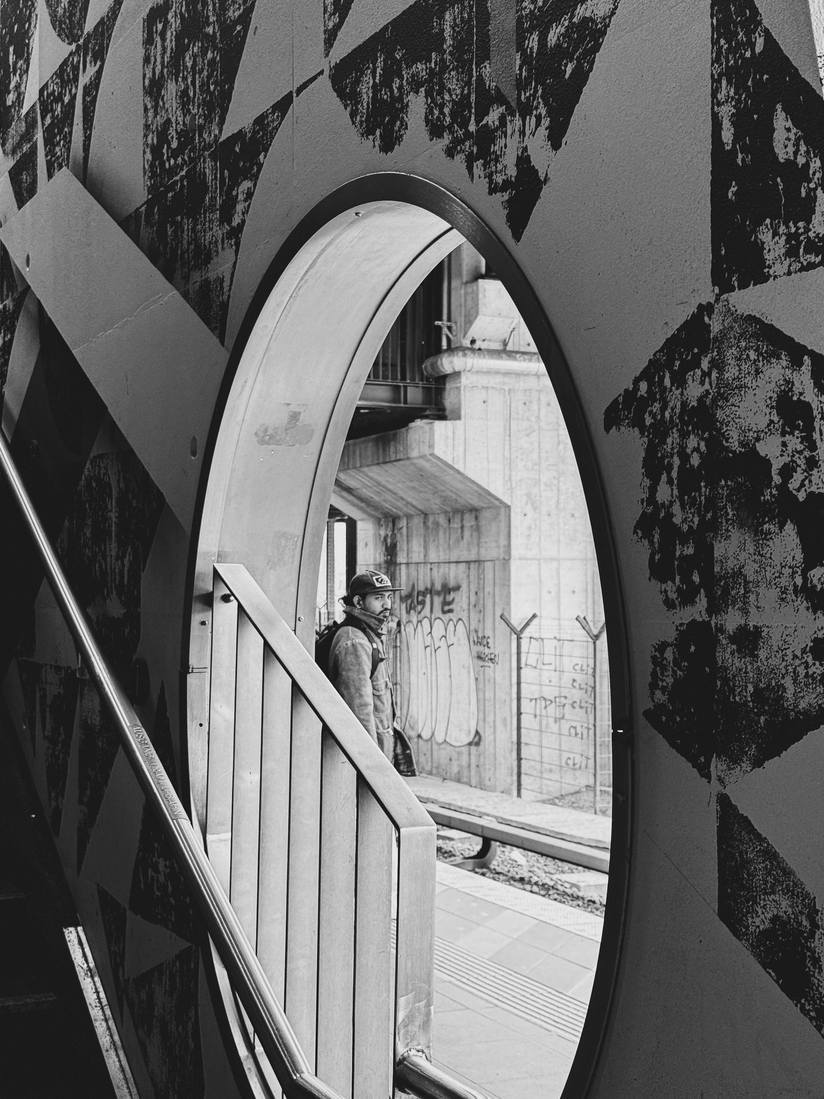 Gratuit Une personne se tient debout dans une gare, vue à travers une ouverture circulaire, les murs étant recouverts de graffitis. Photos