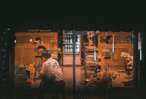 Free Warm ambient lighting inside a café in Bangkok, Thailand, with people dining and floral decor. Stock Photo