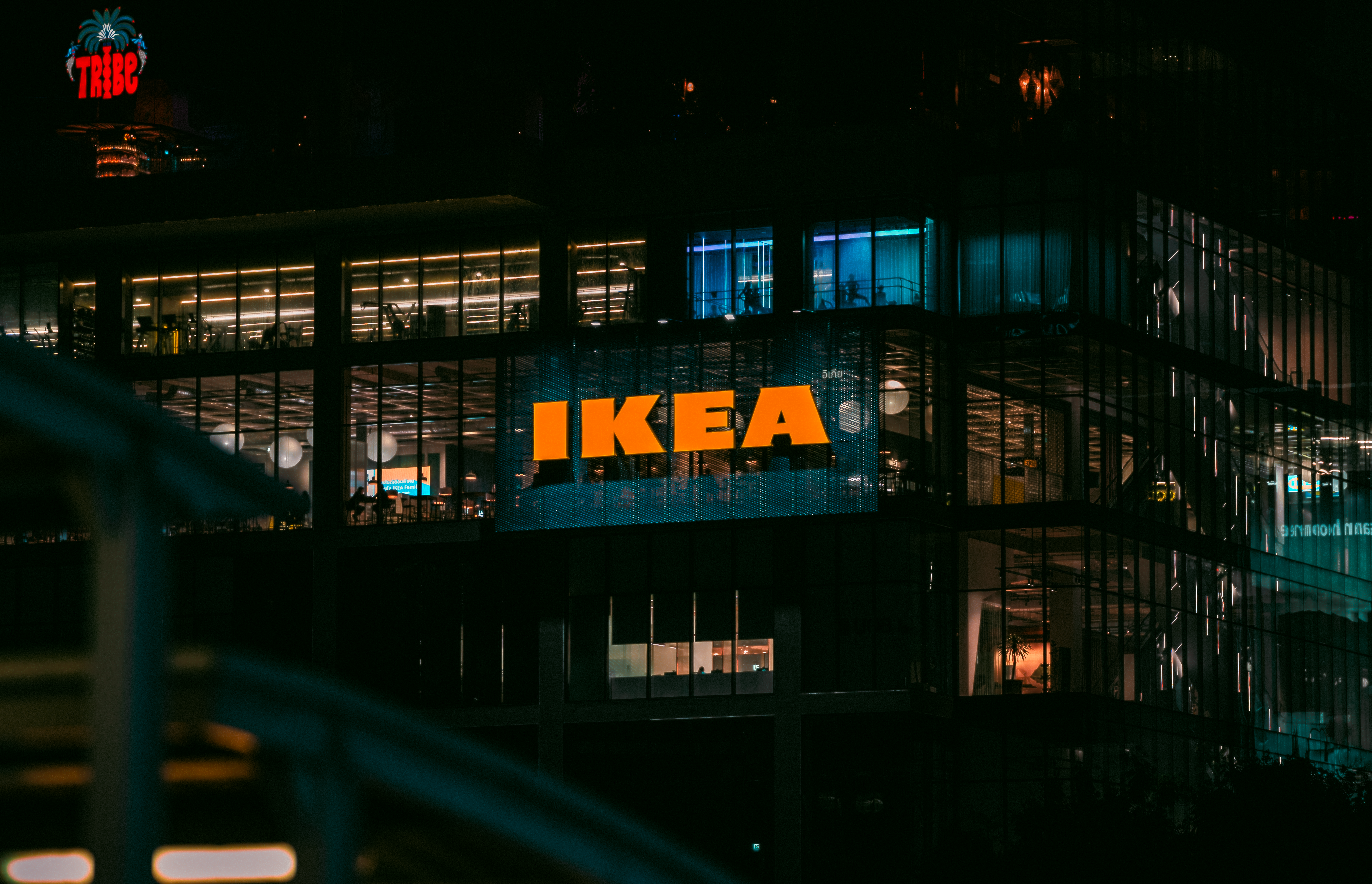 Illuminated view of an IKEA store in Bangkok at night, showcasing vibrant city lights.