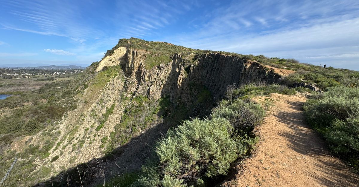 Discover a stunning nature trail with rocky cliffs in Carlsbad, CA under a vibrant blue sky.