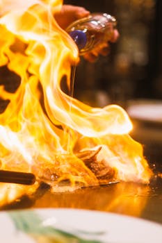 A chef flambés a dish with dramatic flames creating a vibrant cooking scene.